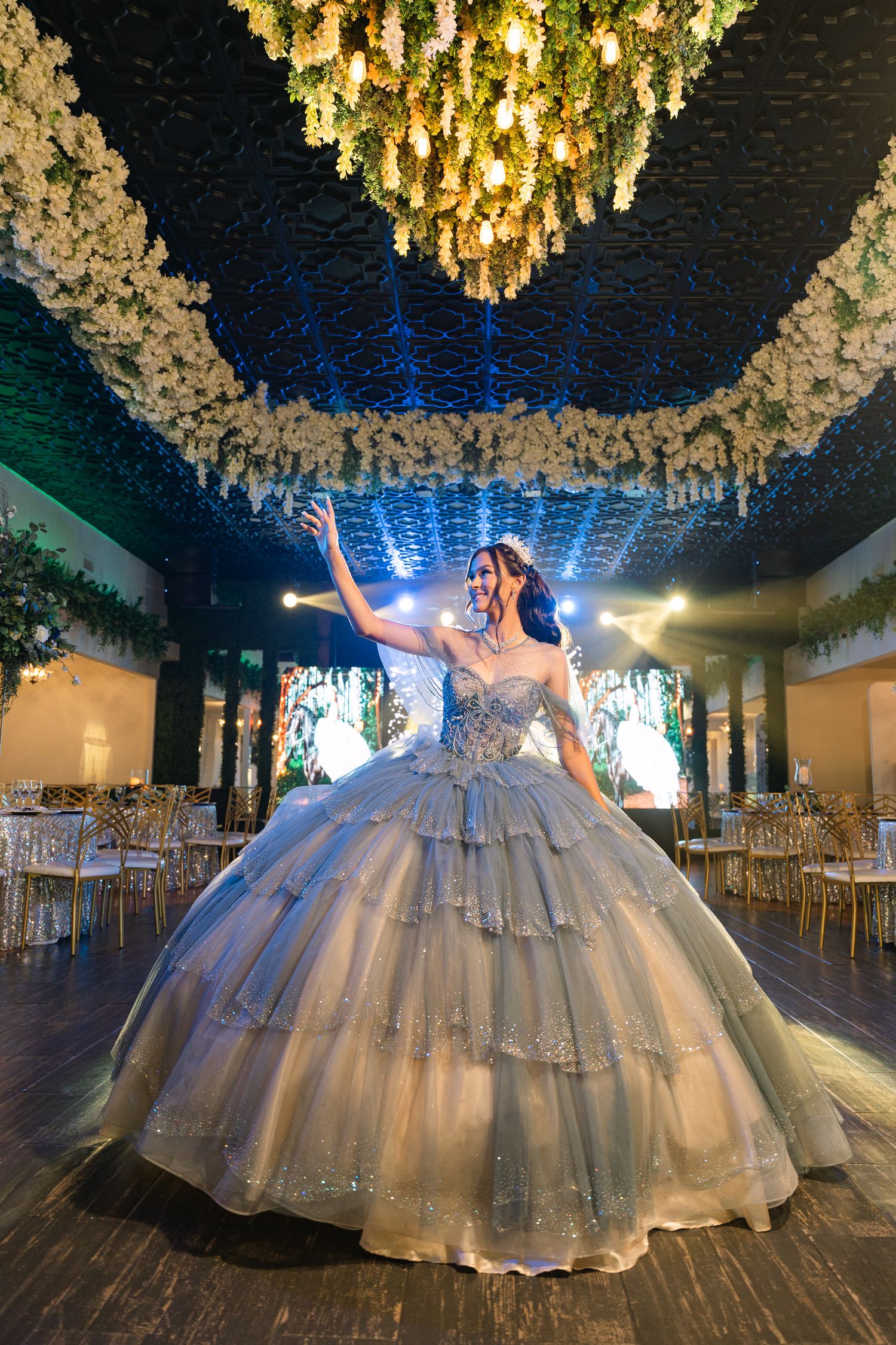 Ballgown dress with flowing tulle skirt and crystal chandelier lighting creating a dramatic scene on dark hardwood floor.