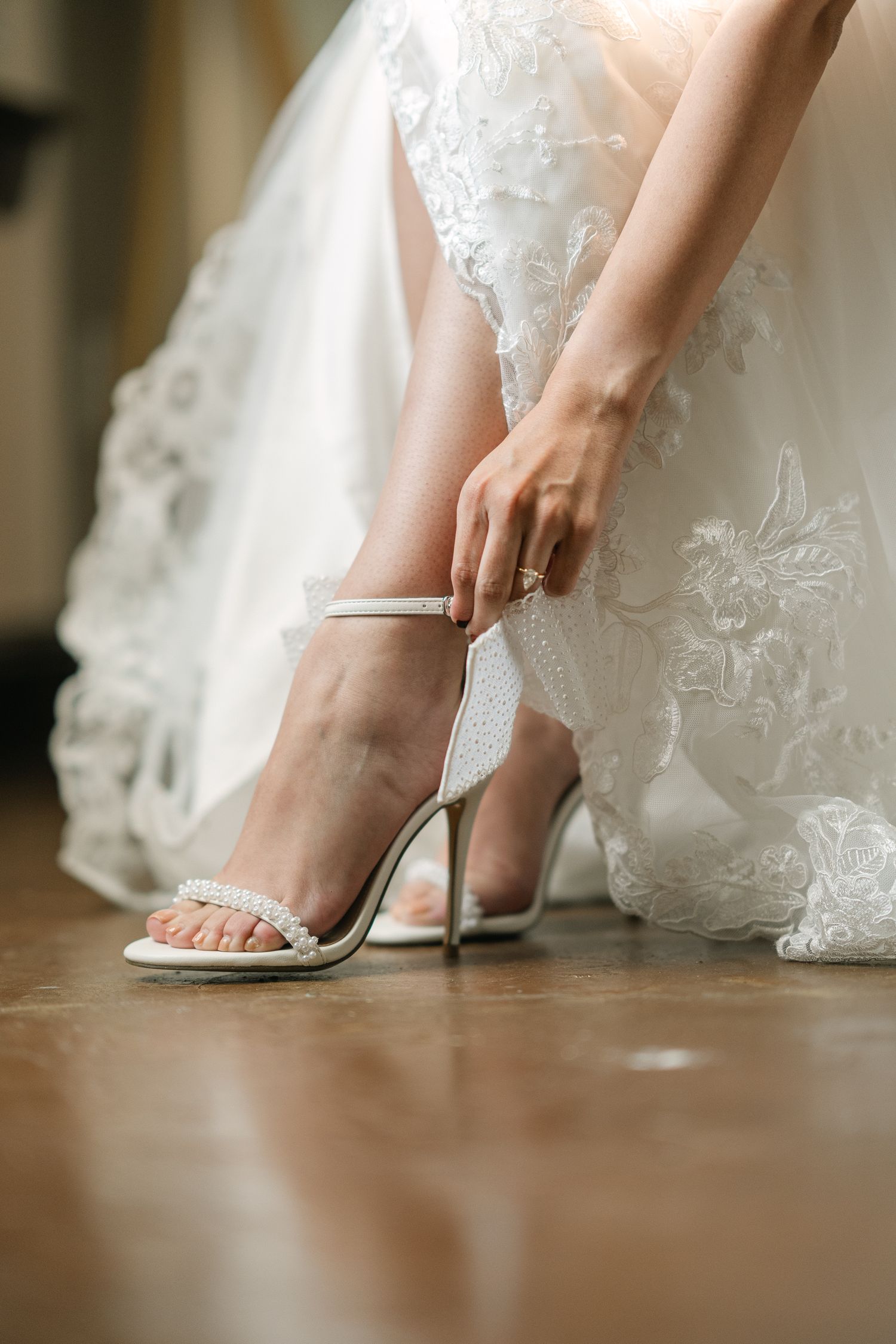 Close-up shots of bride putting on elegant white wedding heels.