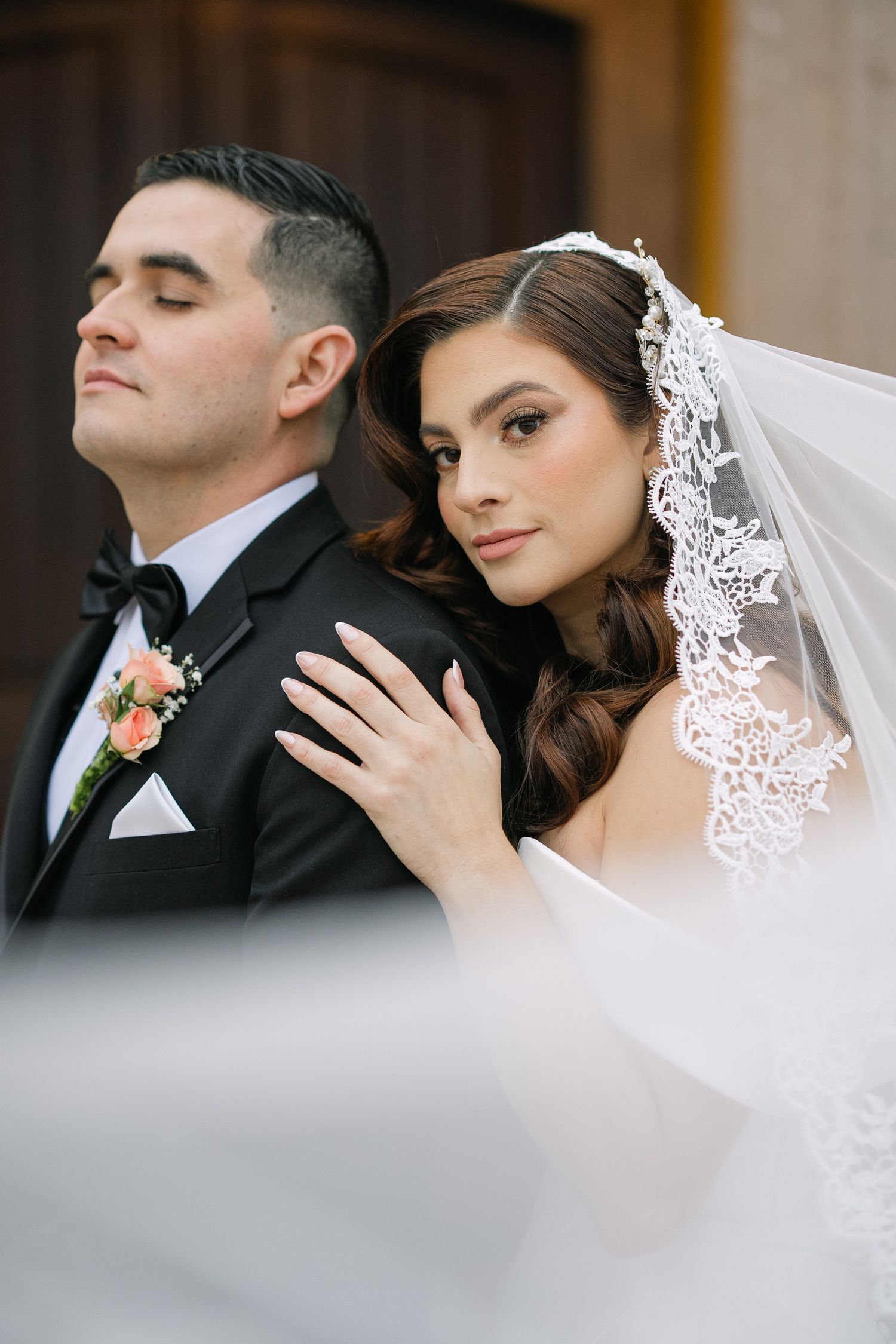 Romantic portrait of newlyweds with bride wearing delicate lace veil.