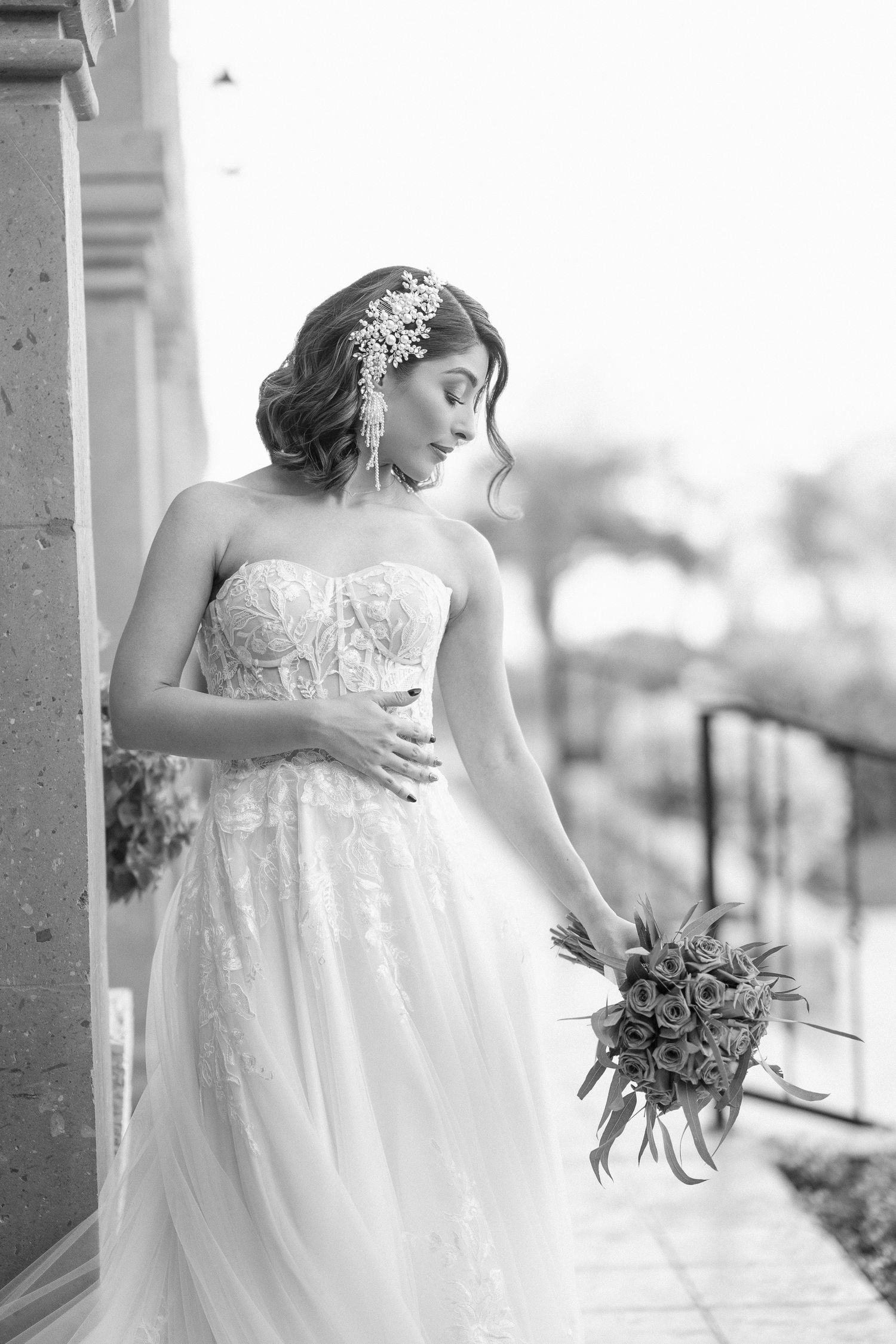 Black and white bridal portrait showing detailed lace gown and floral hairpiece.