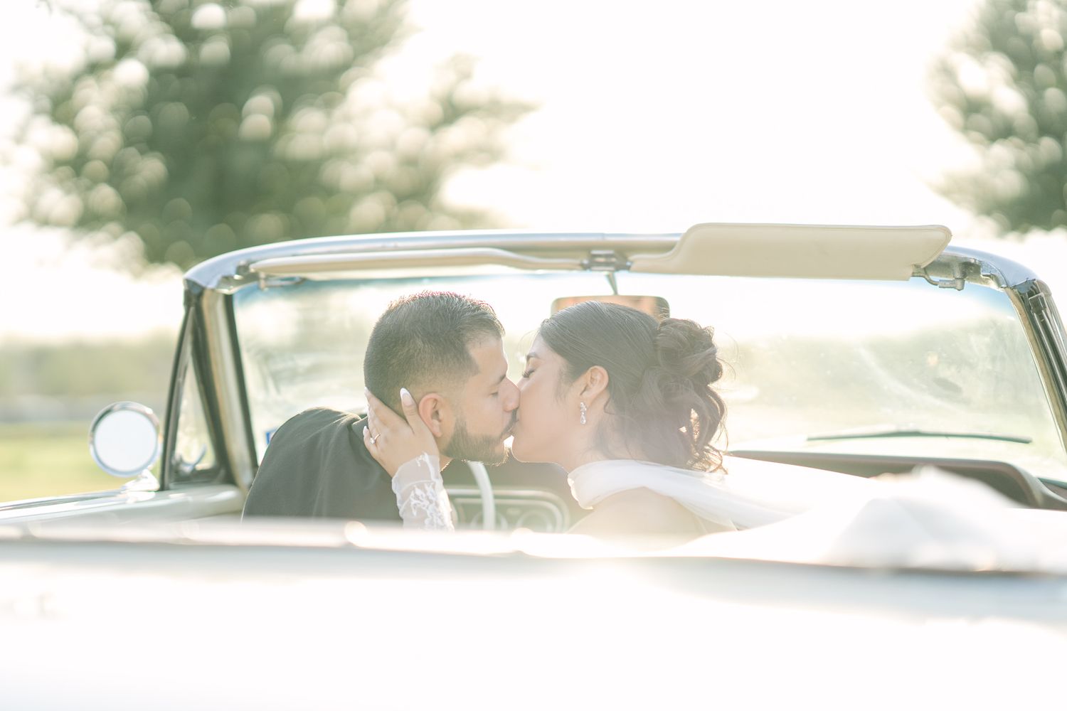 A romantic moment captured in a vintage convertible car during golden hour.
