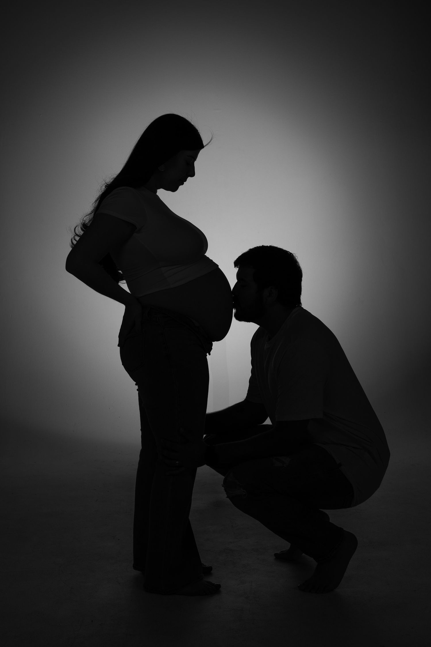 Silhouette of expectant couple sharing an intimate pregnancy moment.