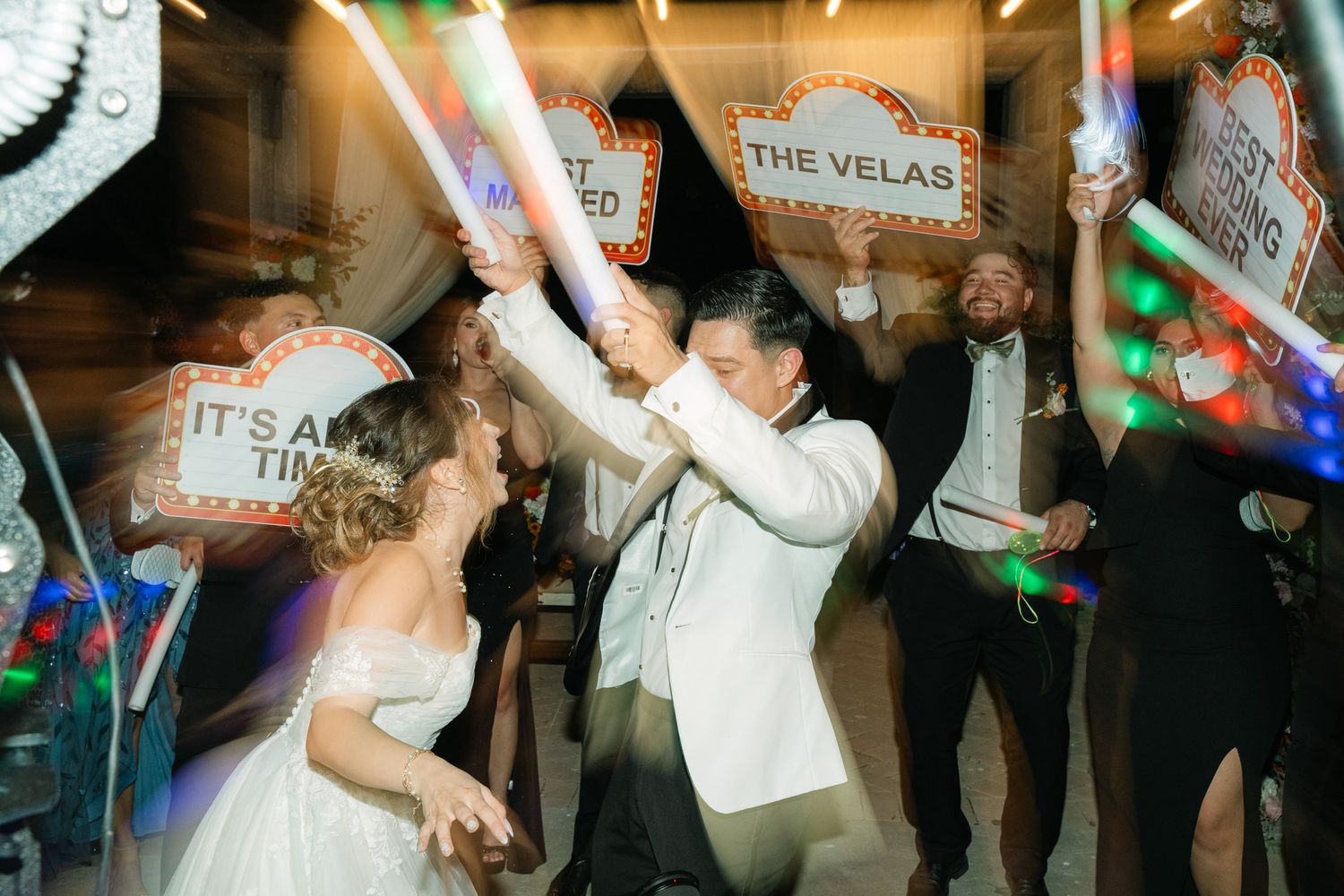 Wedding reception celebration with guests dancing under colorful lights in a fun party atmosphere.