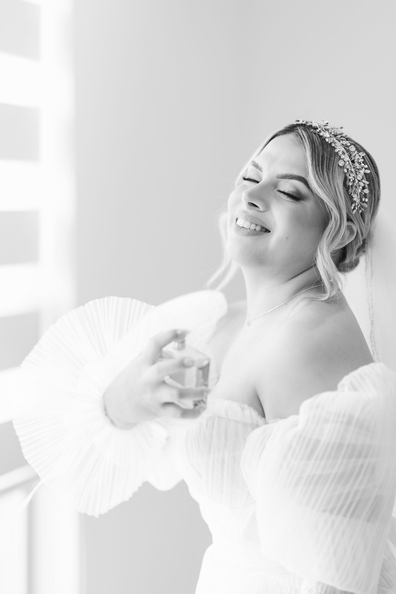 A joyful moment captured in black and white as a bride smiles while wearing an off-shoulder gown.