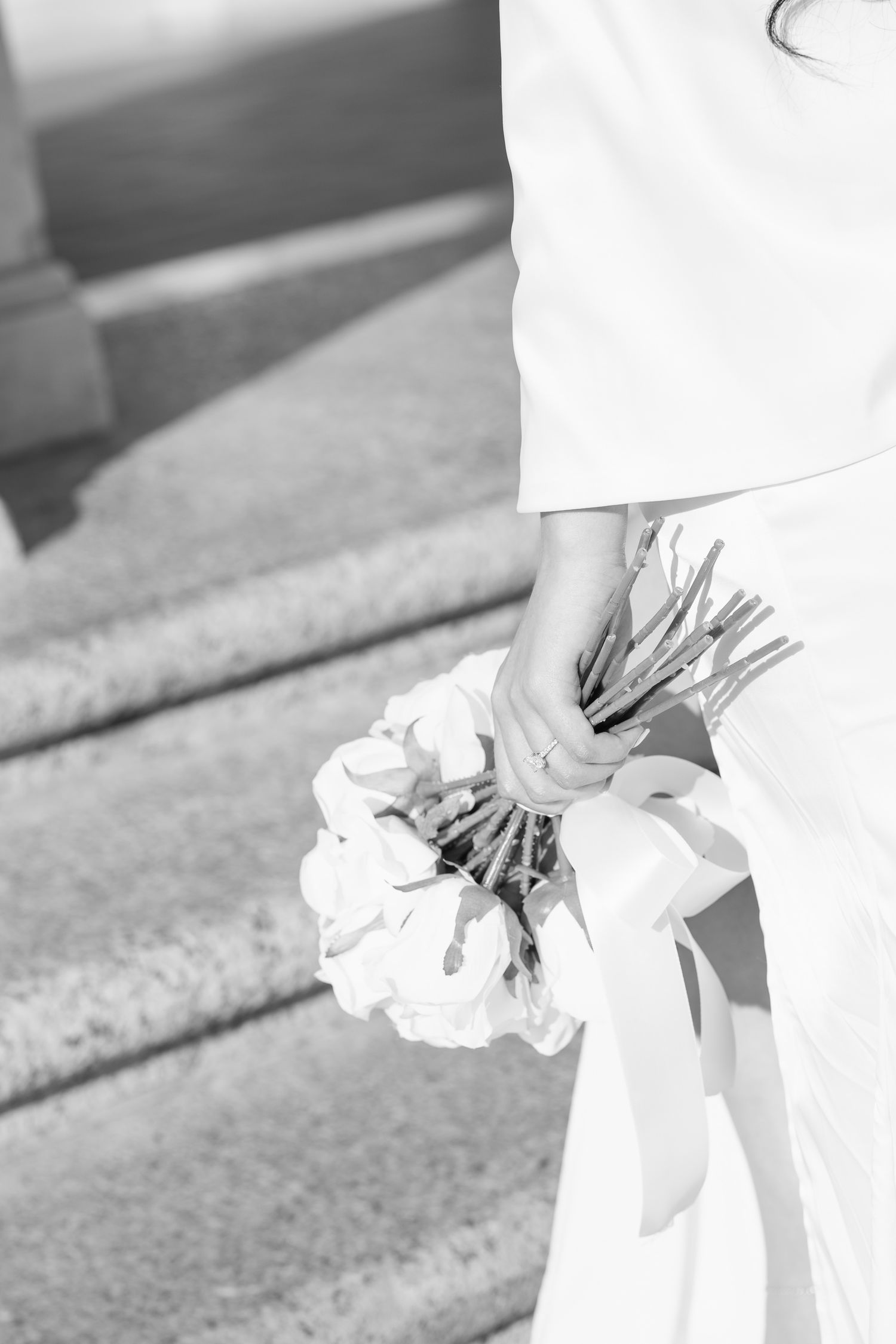 Black and white image of hands holding delicate white flowers against a textured background.