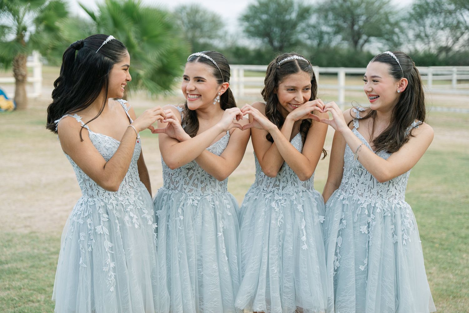 Group wearing matching light blue dresses pose together in an outdoor garden setting.
