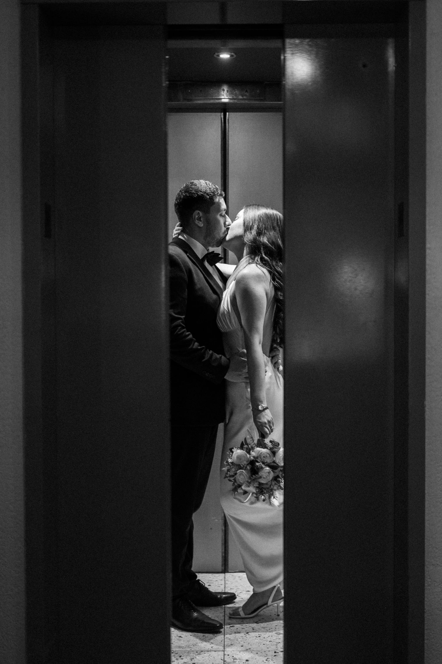 Dramatic black and white elevator portrait showing a romantic embrace.