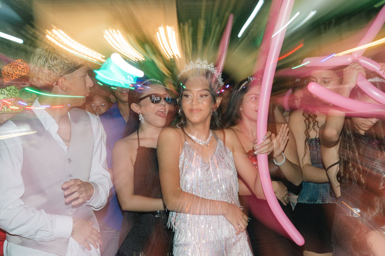 A blurred motion party photo with colorful lights and balloon decorations.