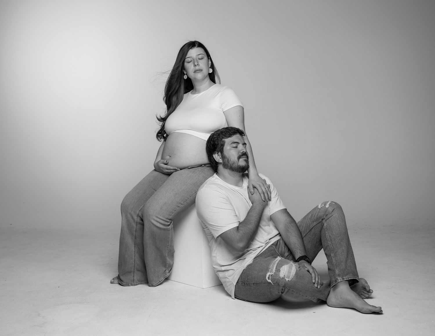 Artistic black and white maternity photo with couple in casual attire.
