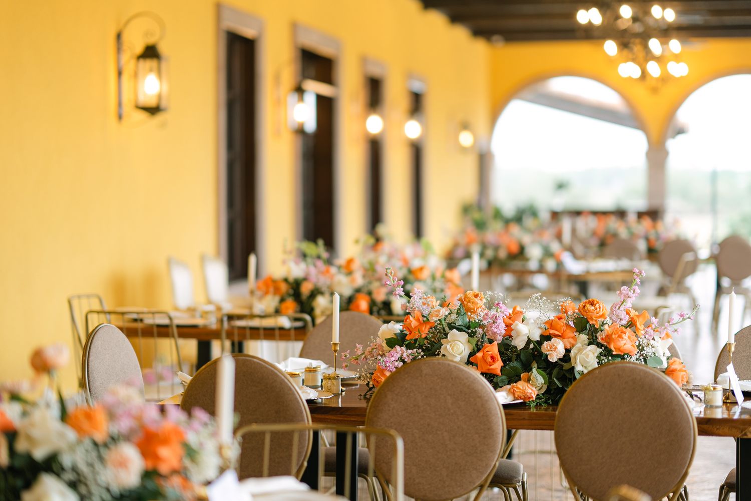 Wedding reception venue with peach floral centerpieces and elegant table settings.