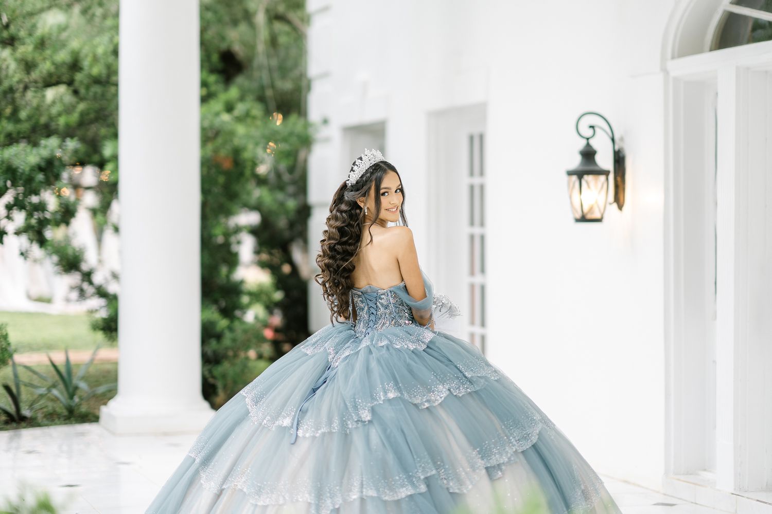 Light blue ballgown photographed against white columns and architecture in an elegant outdoor setting.