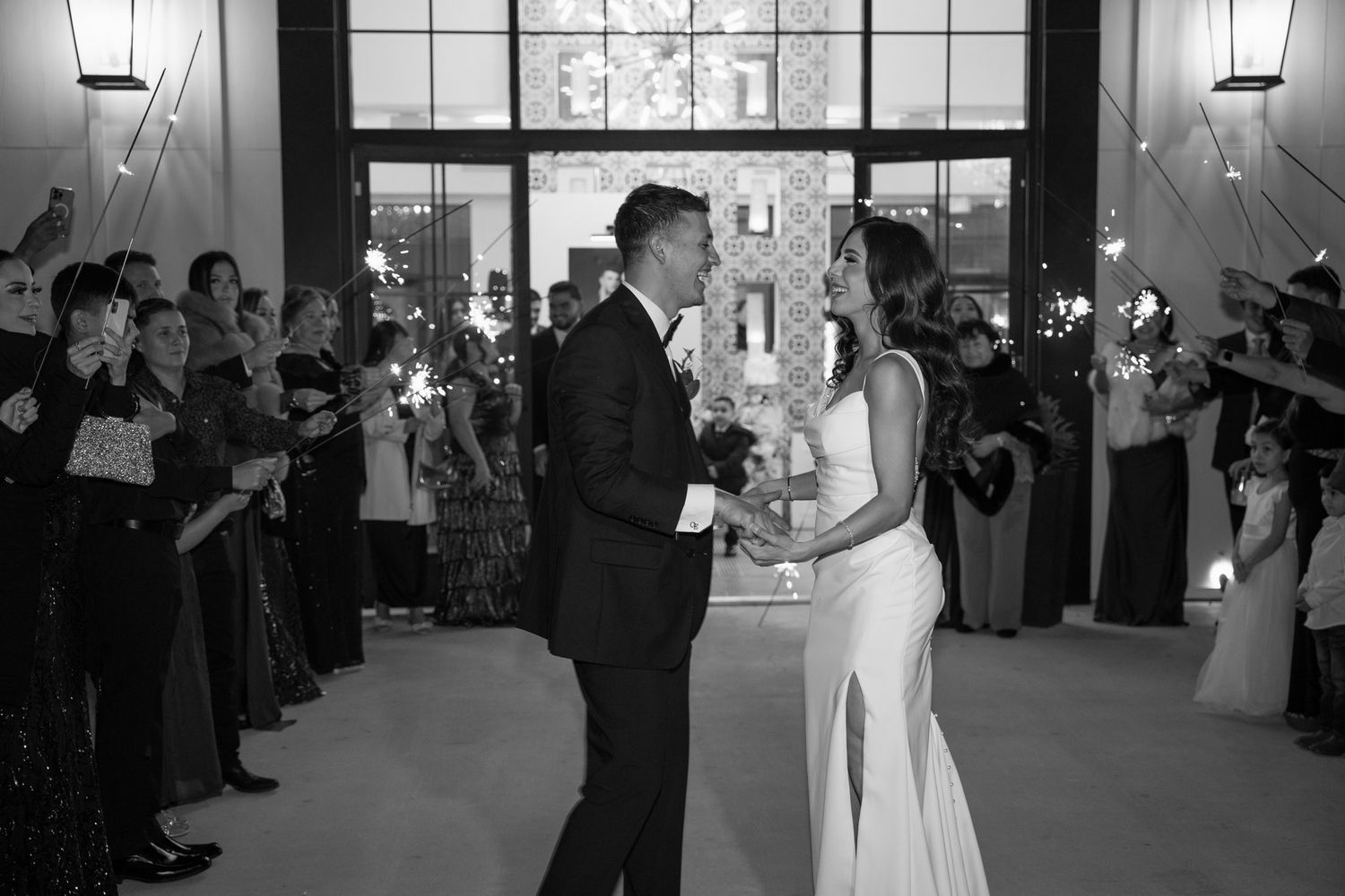 Wedding guests hold sparklers during couple's first dance in black and white.