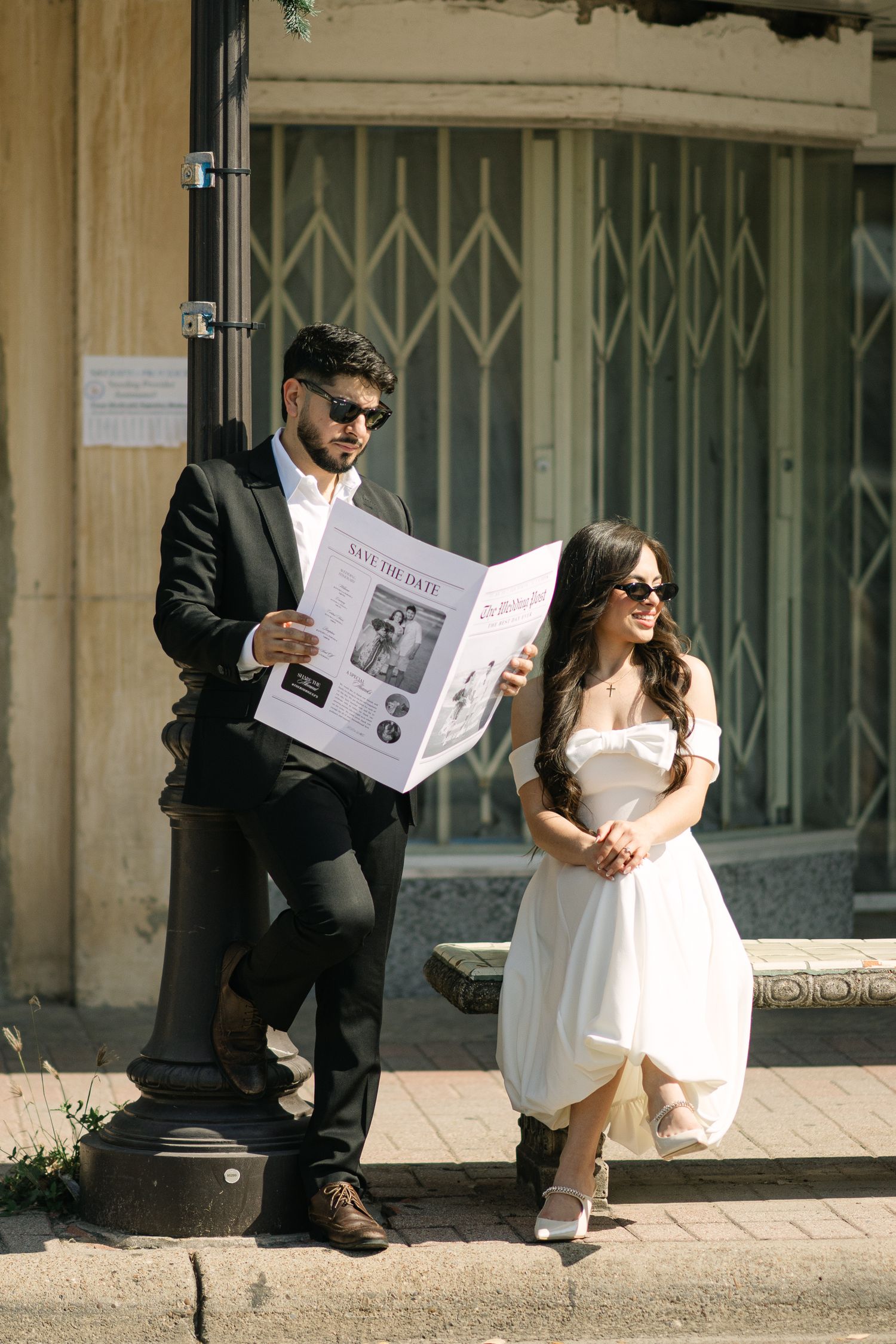 People sitting on steps reading a newspaper together at an ornate building entrance.