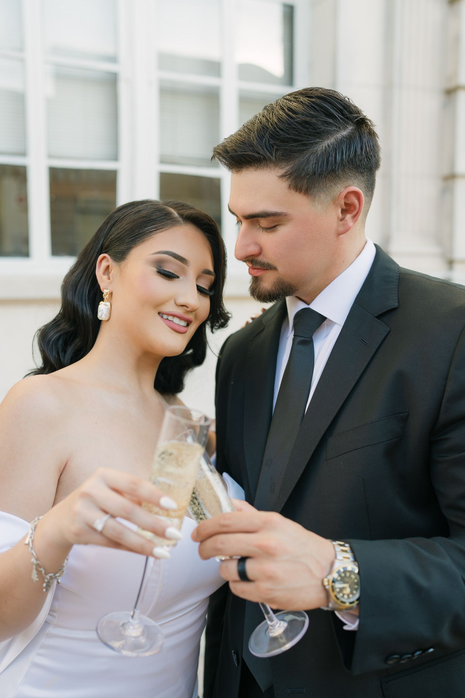 Elegant couple sharing champagne moments in formal wedding attire.
