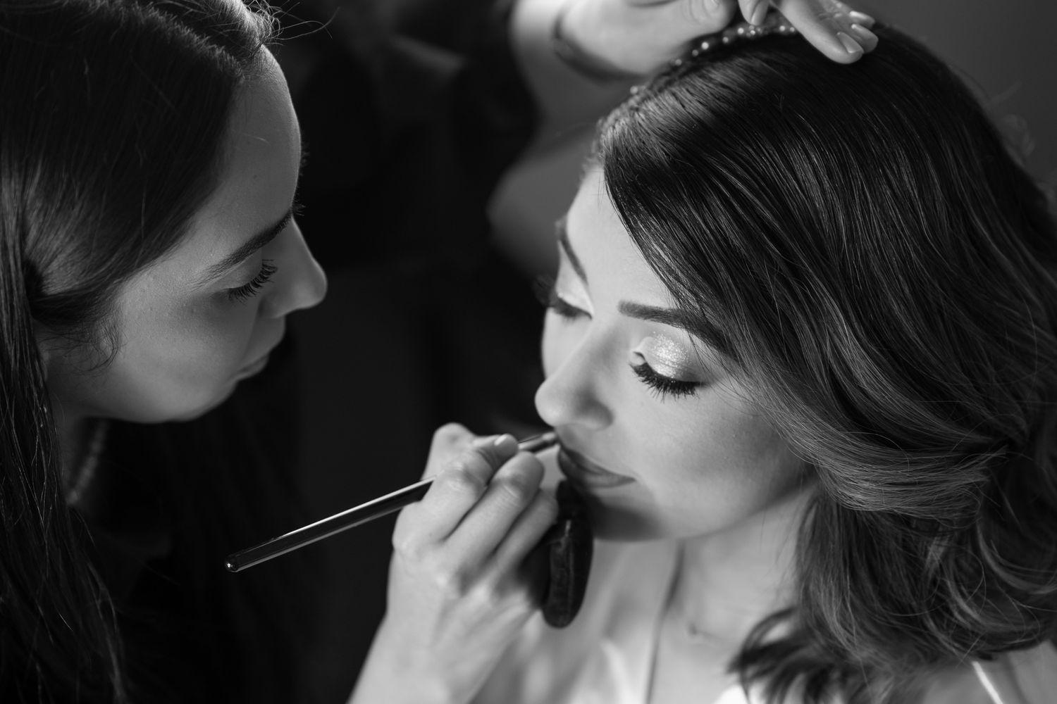 Black and white series of makeup artist applying bridal makeup.