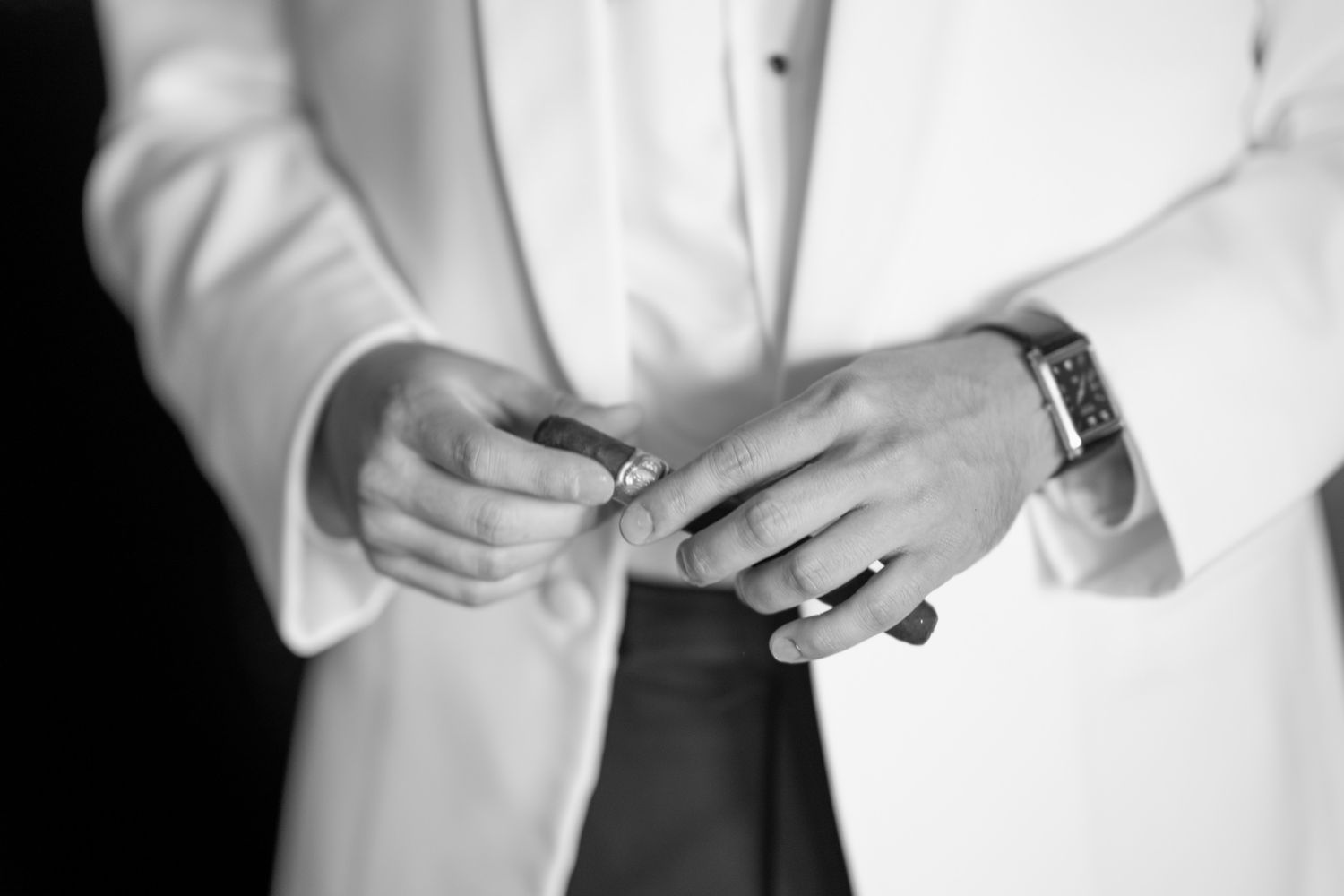 Detail shots of groom adjusting white tuxedo jacket and cuffs.
