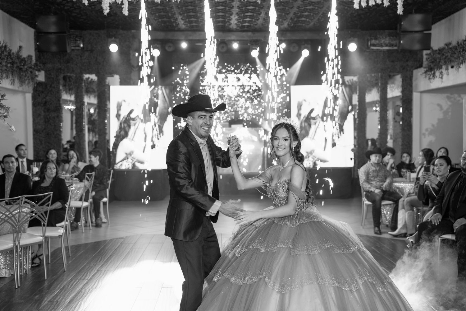 A black and white photo of a dance performance at an elegant celebration with pyrotechnic effects.