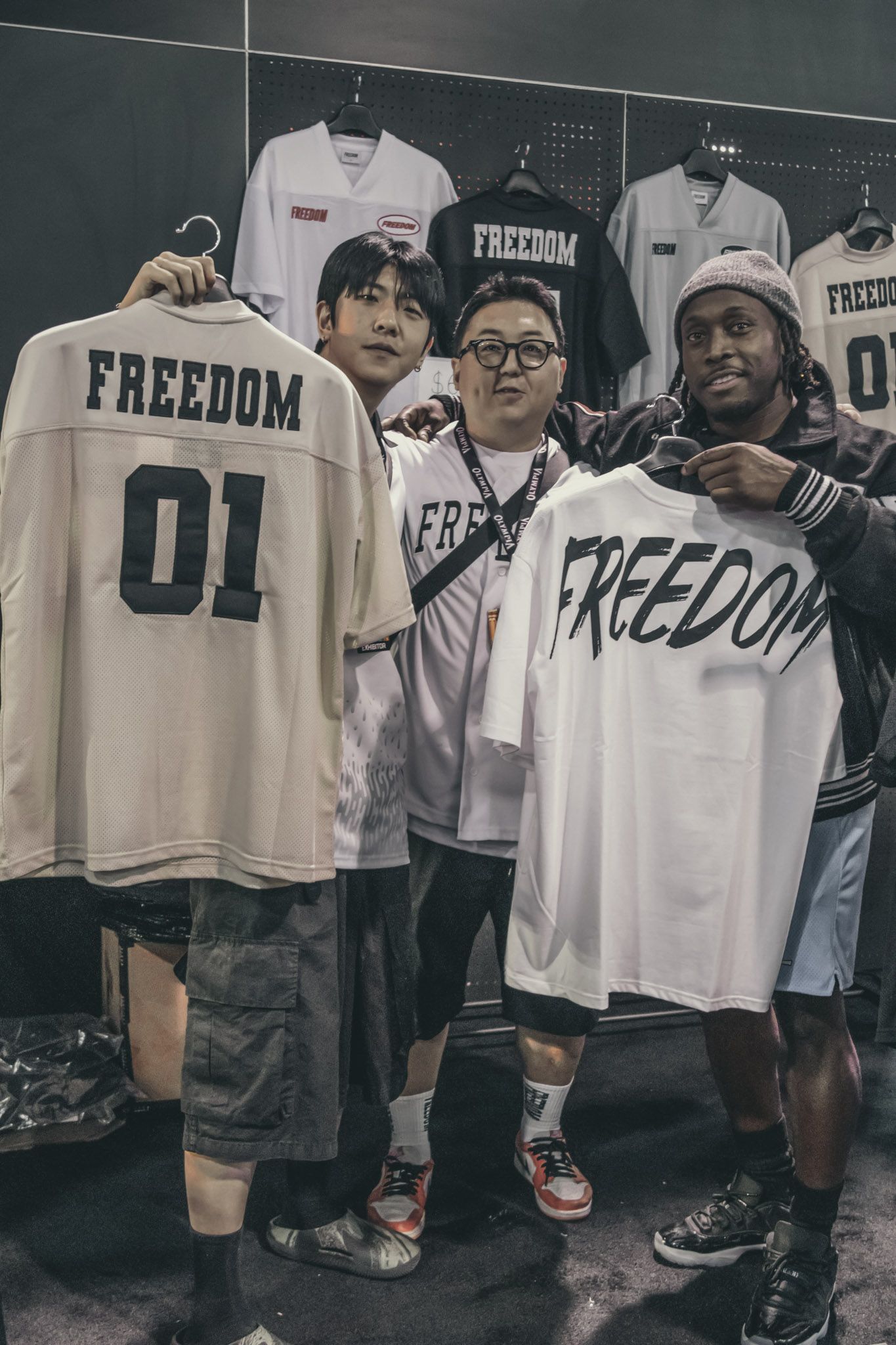 Display of white jerseys with 'FREEDOM' text hanging on clothing racks at a retail event.