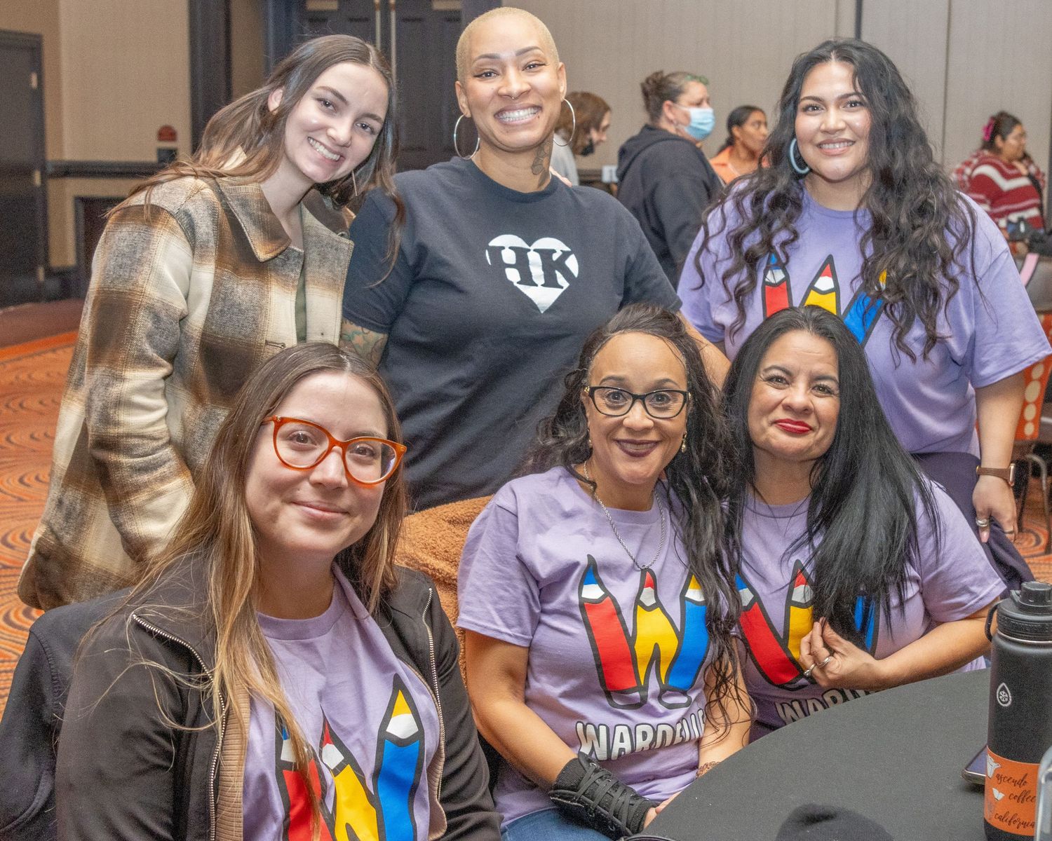 Students wearing colorful t-shirts smile together at a school event.