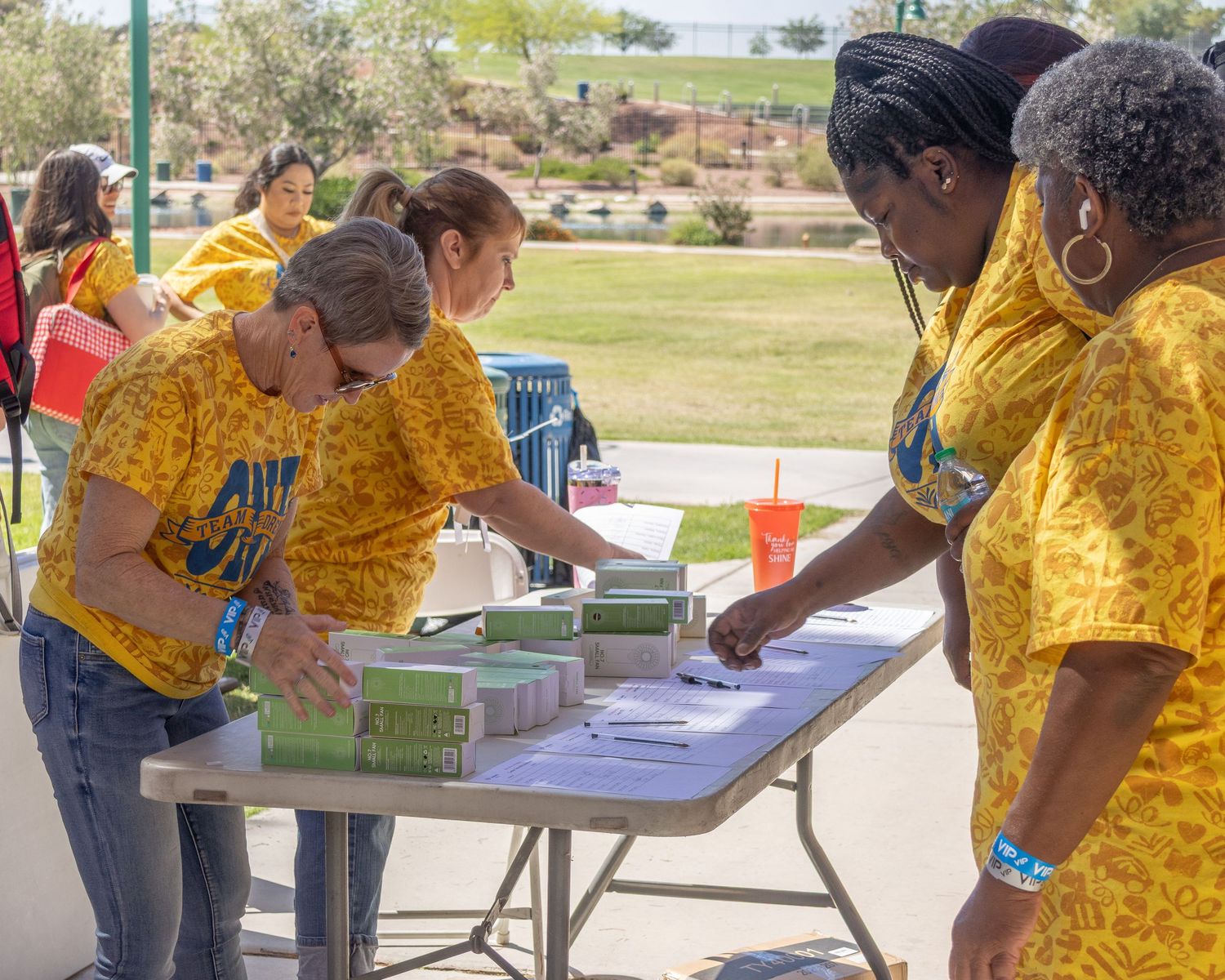 Participants in matching yellow shirts working at activity tables during an outdoor event.