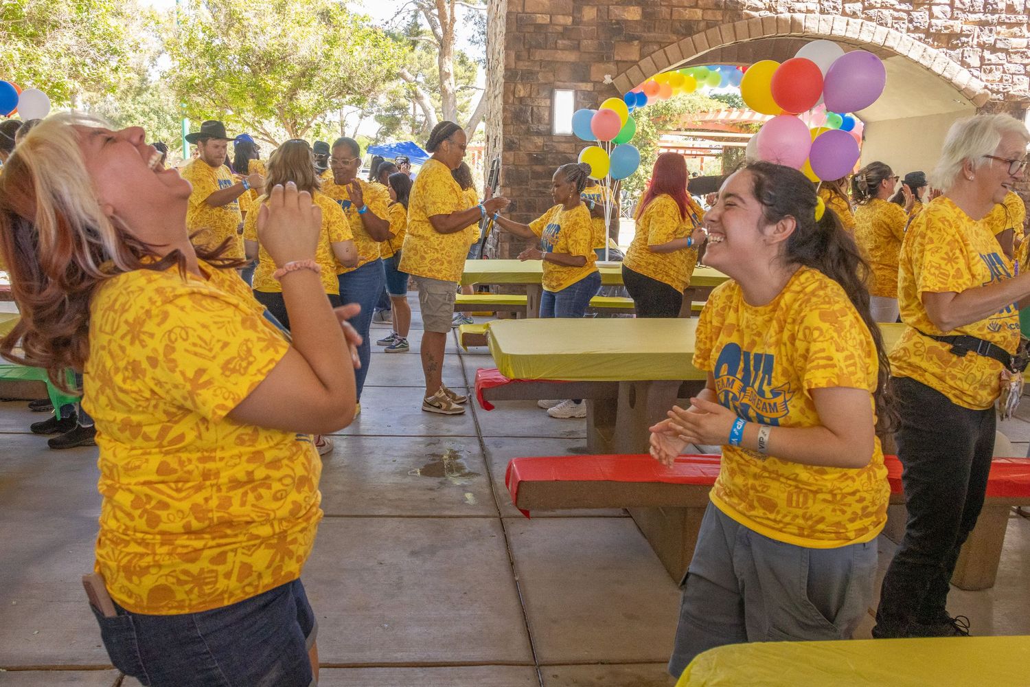 Group wearing matching yellow shirts gathered under a covered outdoor area for activities.