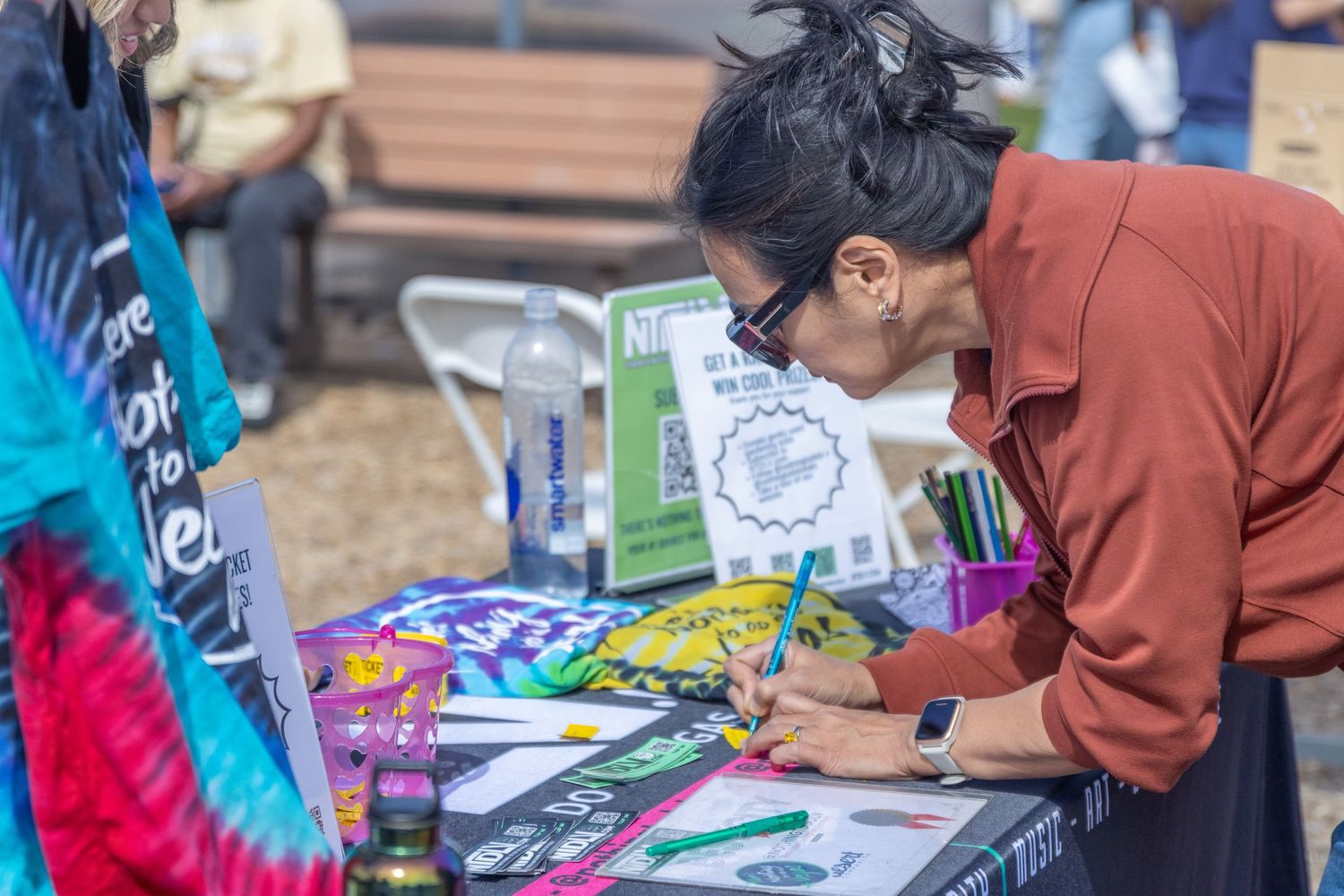 Students participate in an outdoor commitment signing activity with pens and paperwork at tables.