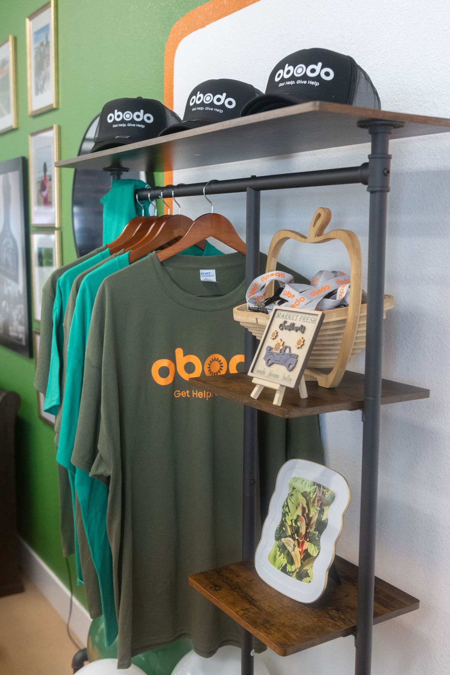 Retail clothing display rack showing green t-shirts and caps with Abedo branding in a minimalist store setting.