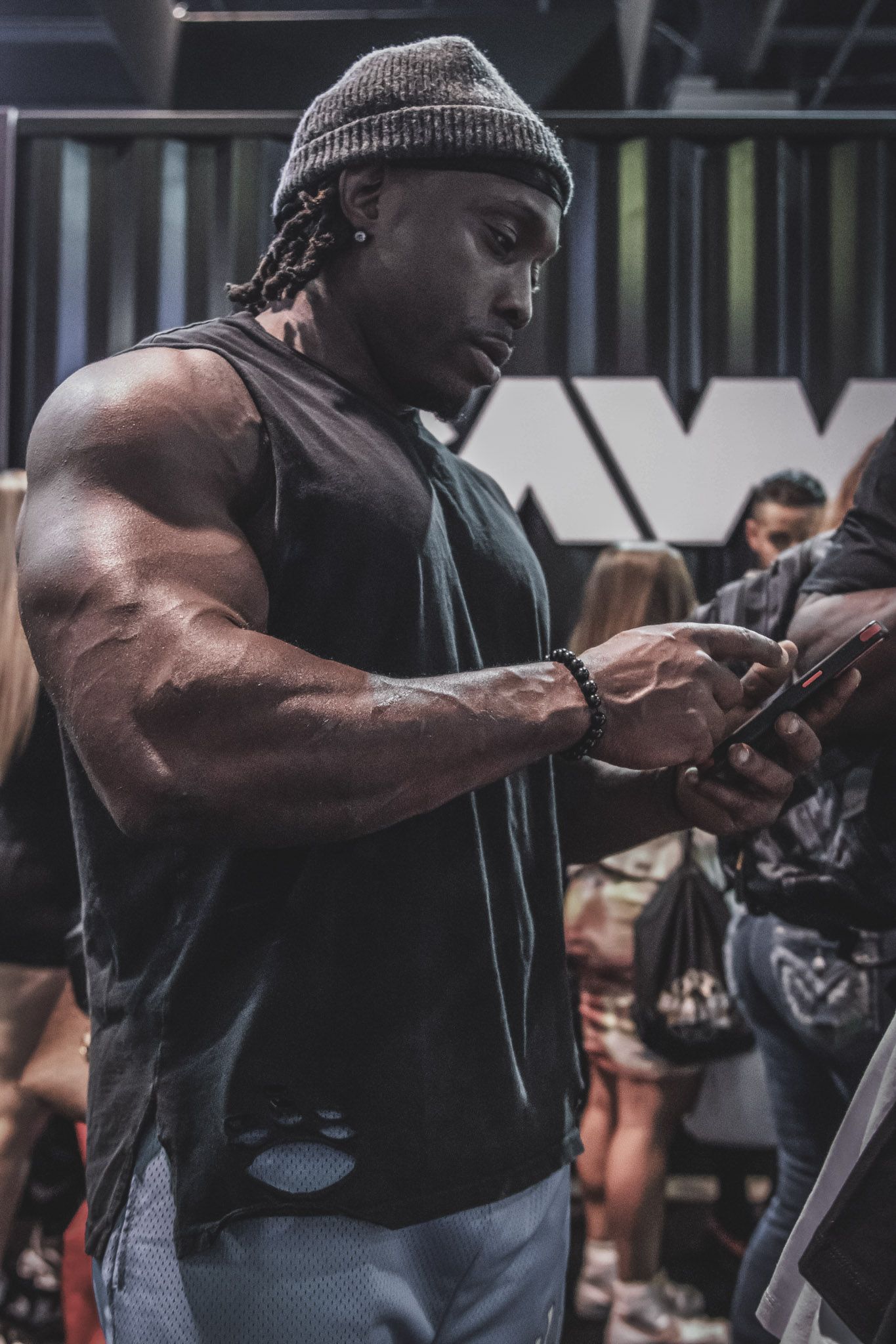 Strong bodybuilder demonstrates athletic movement sequence in black tank top at fitness facility.