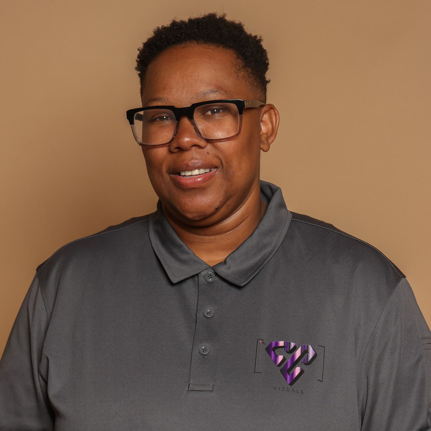 Professional headshots of person wearing gray polo shirt and glasses against beige background.