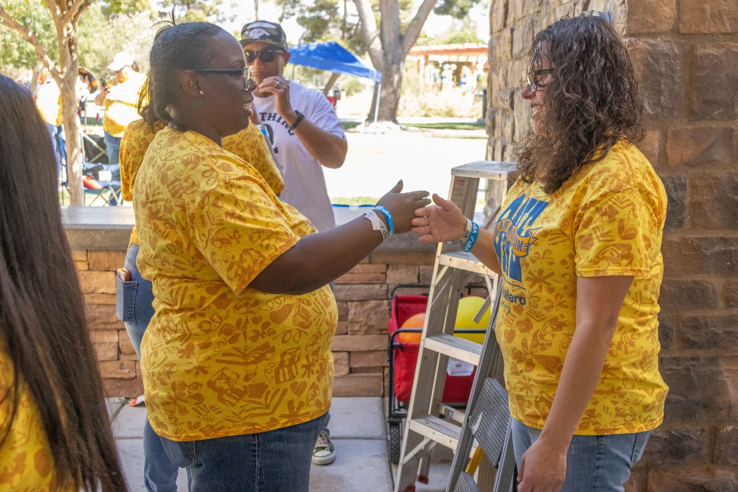 Attendees in bright yellow shirts participating in outdoor activities under a covered pavilion.