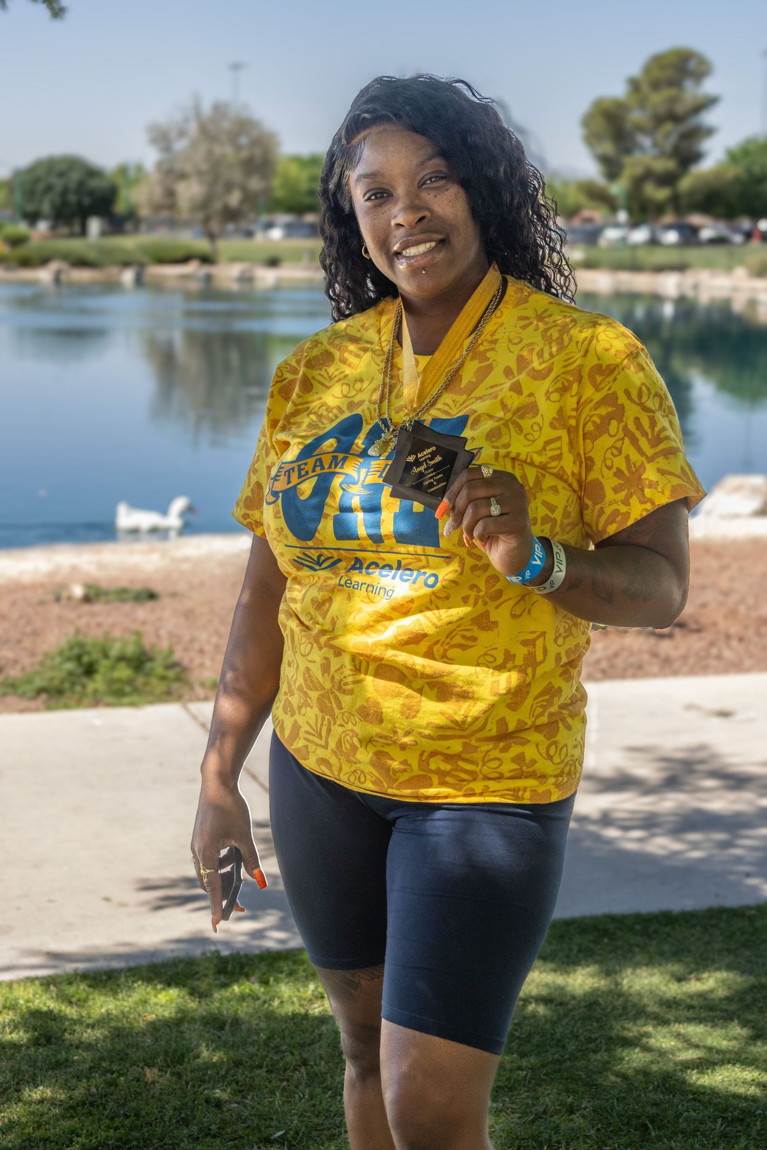 People in bright yellow VIP shirts gathered near a lake for an outdoor event.