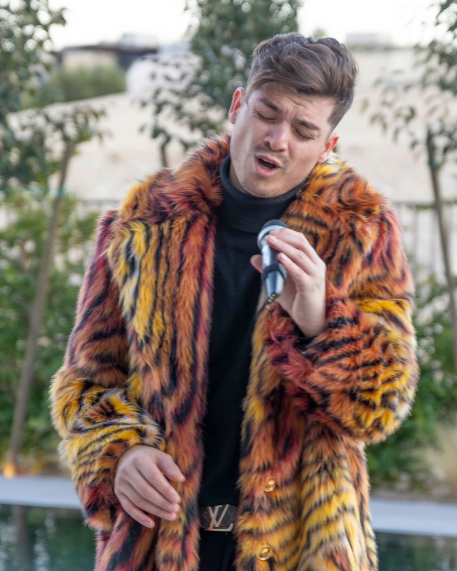Person wearing a striking orange and black tiger print fur coat posing outdoors.