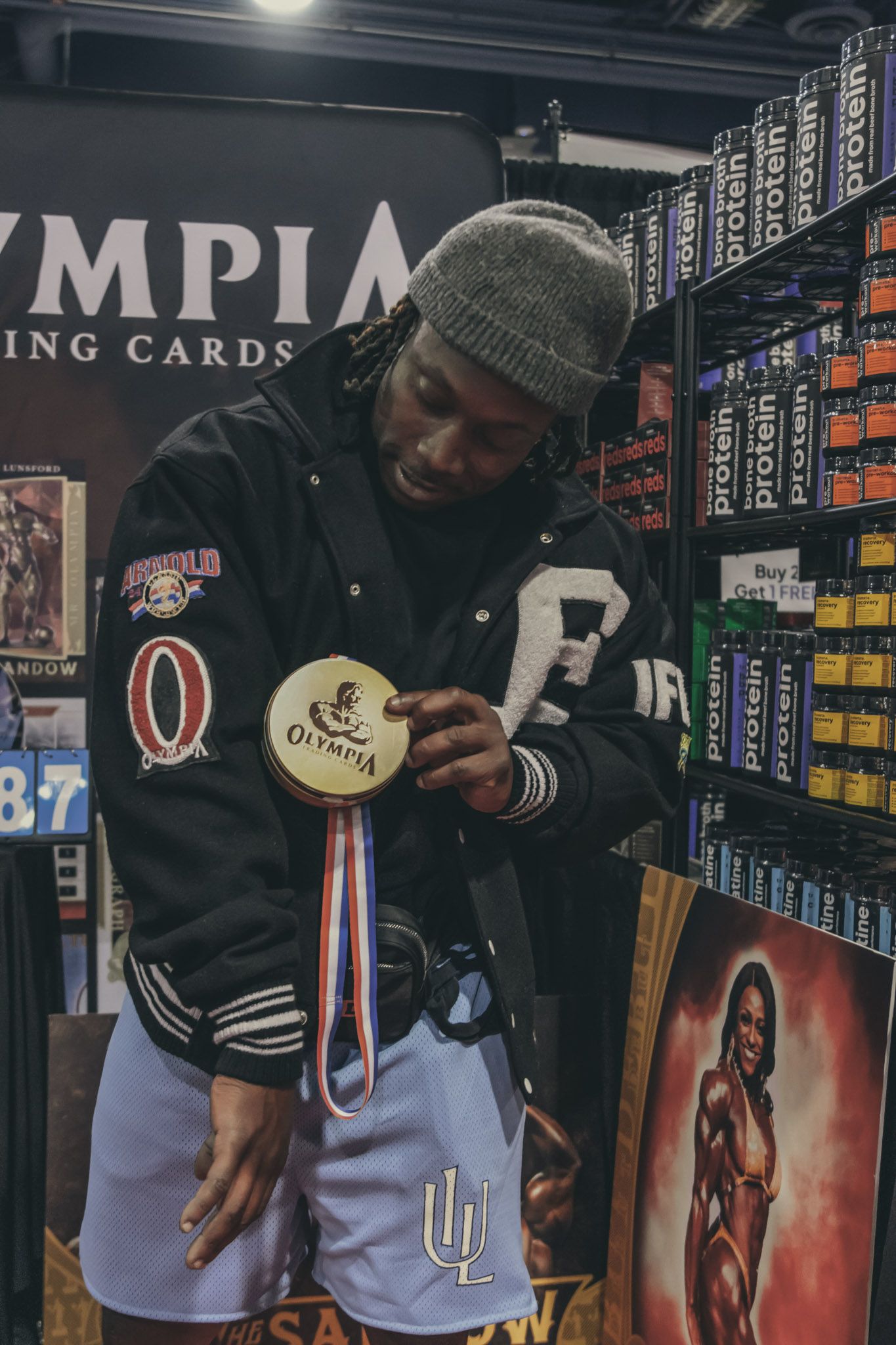 Person browsing trading cards in a hobby shop with shelves of merchandise behind them.
