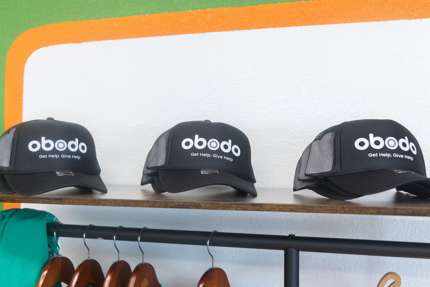 Display rack filled with Obedo brand baseball caps in black color arranged neatly on shelves.