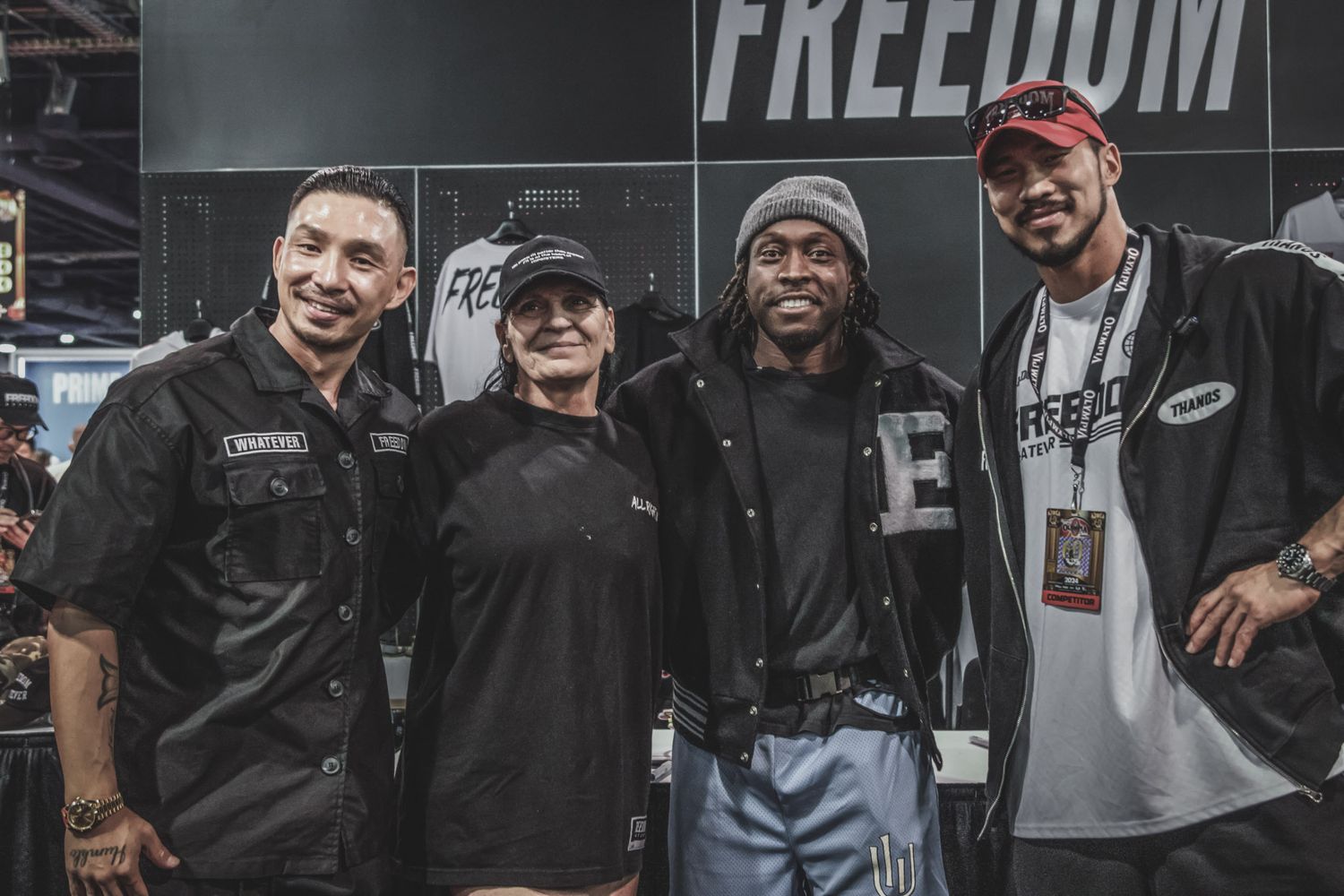 A group of people wearing dark clothing and baseball caps pose together in a casual setting.