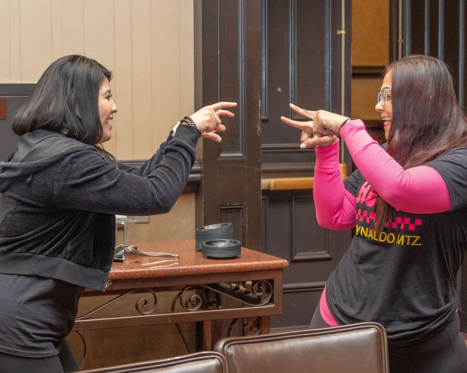 People gesturing and dancing during indoor social gathering.