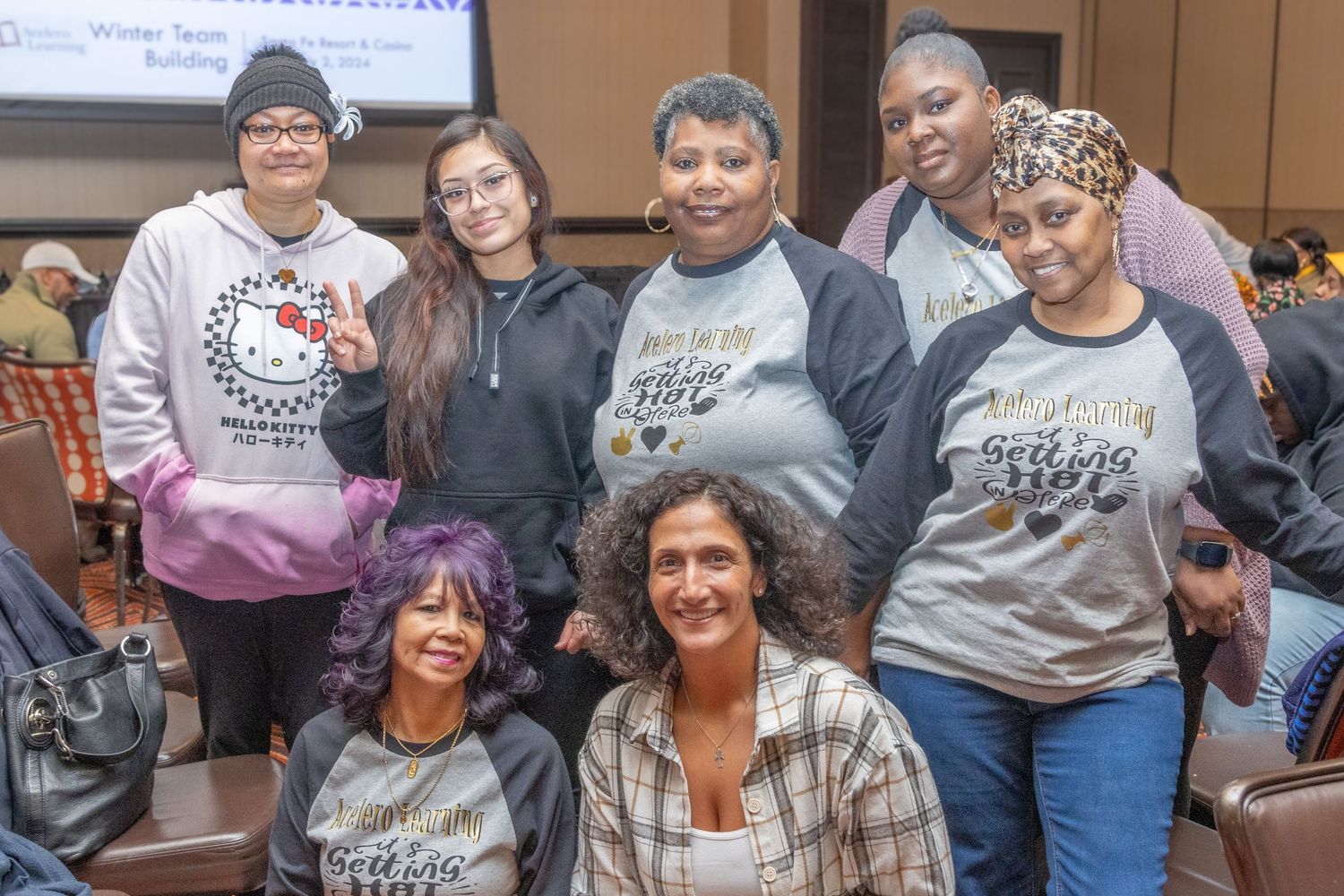 Diverse group of students smiling and socializing during a community event in an auditorium.