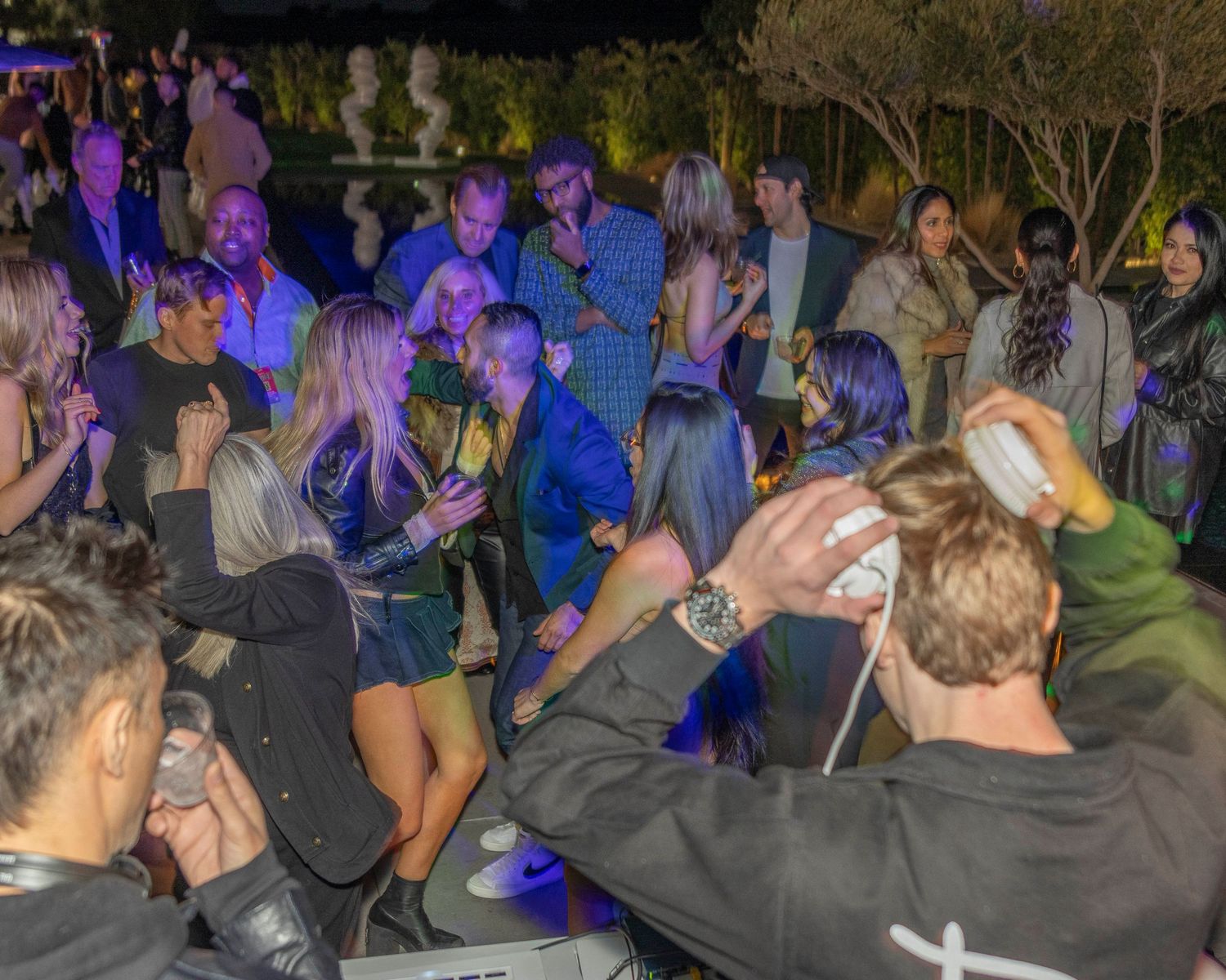 Crowd gathered at a nighttime outdoor event with blue lighting effects.