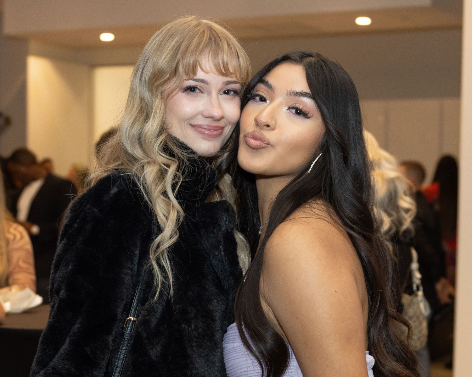 Stylish guests taking photos together at an indoor social gathering.