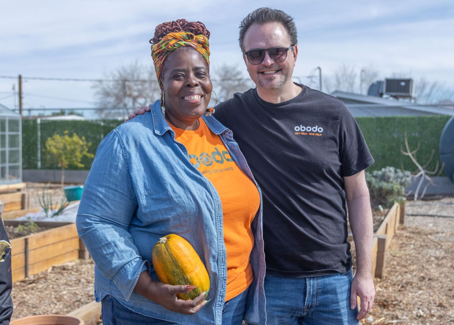 People working together in a community garden setting with raised planting beds visible in the background.