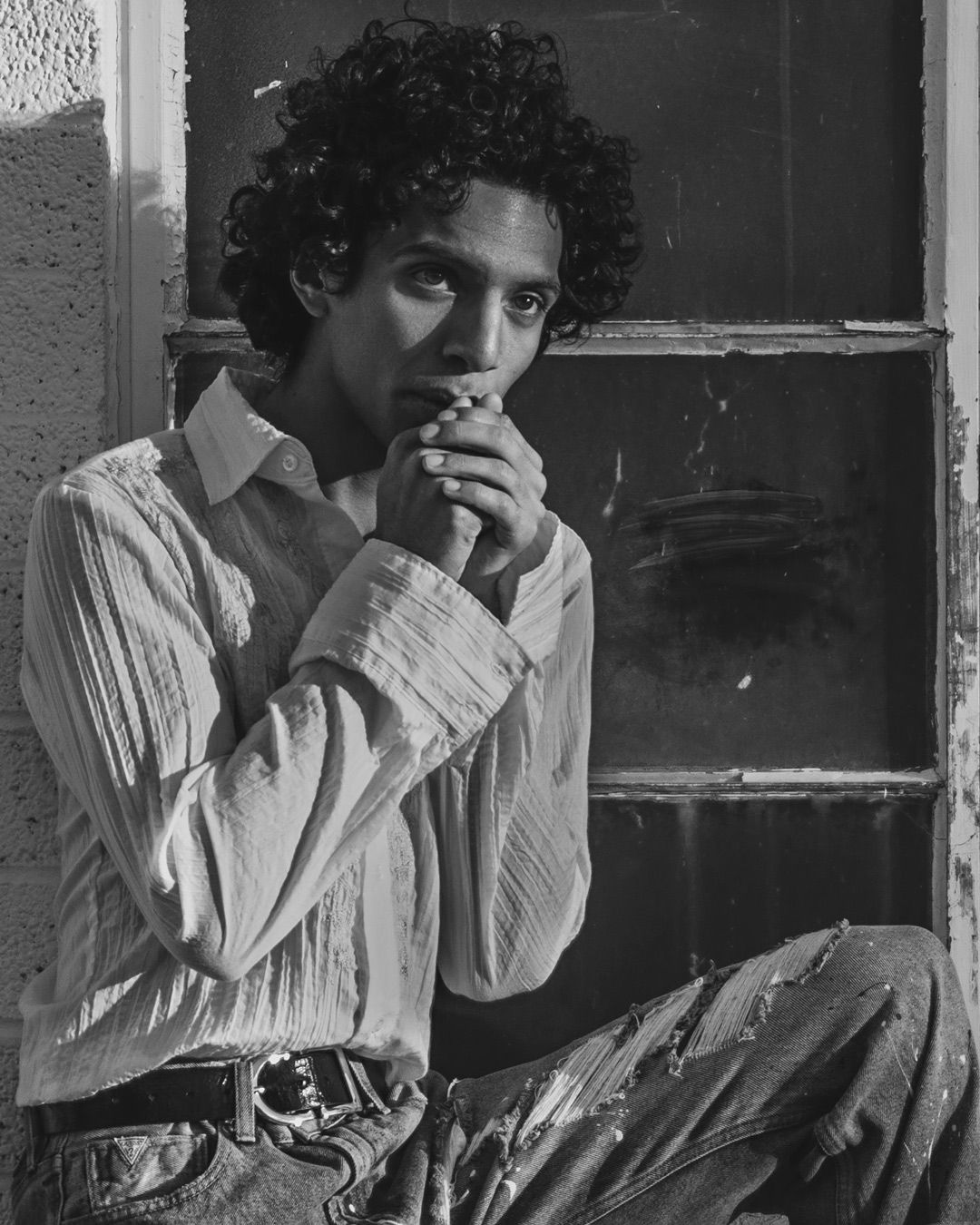A sequence of four black and white photographs showing someone seated by a window smoking a cigarette.