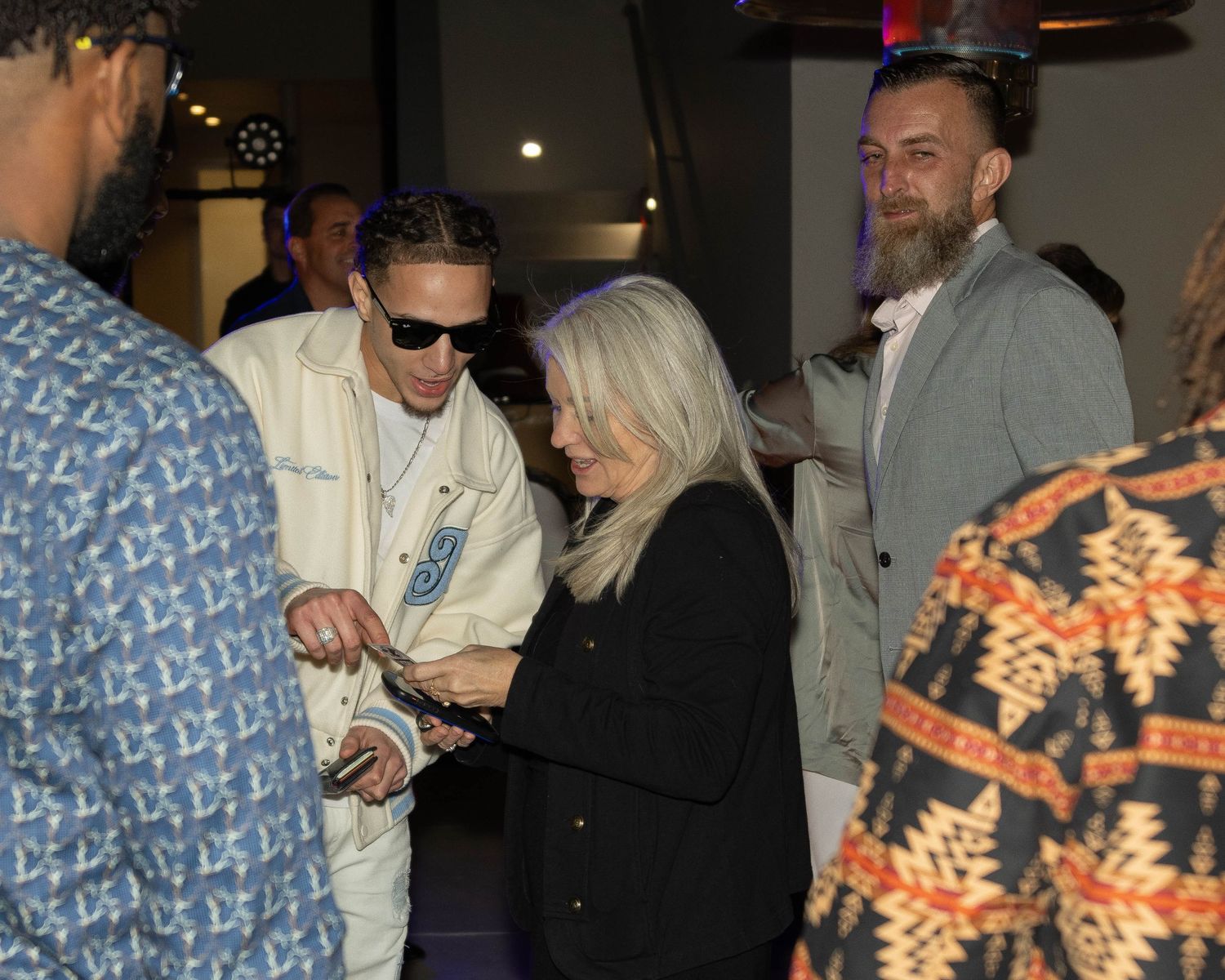 Attendees in casual attire mingling at a dimly lit evening event.