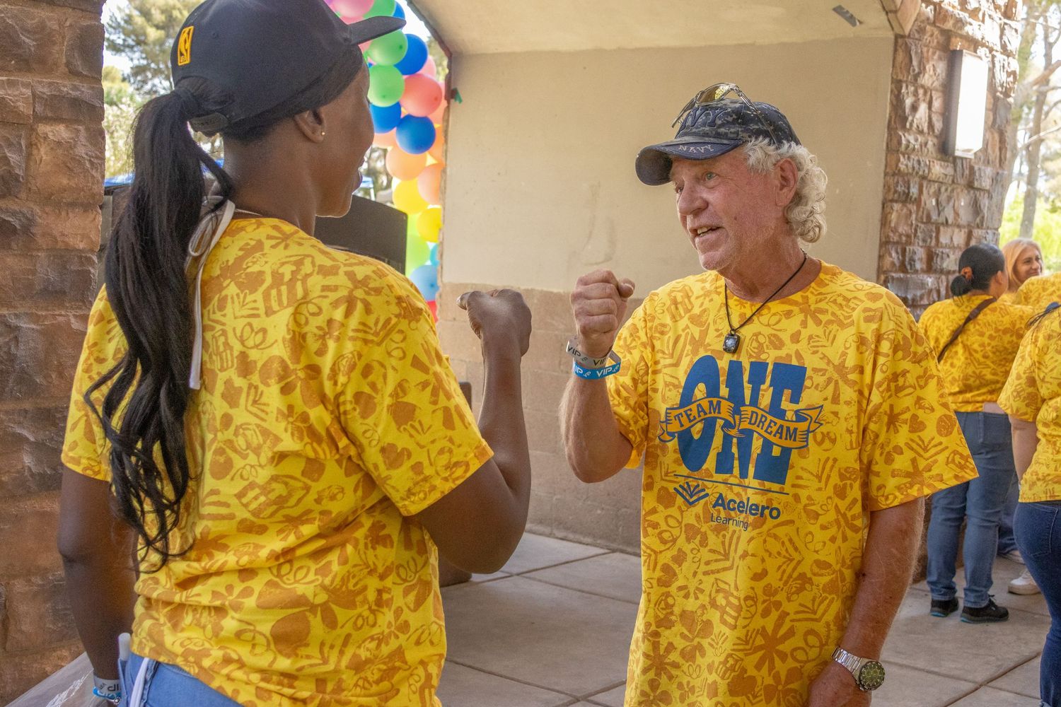 People wearing matching yellow t-shirts gathering at an outdoor venue.