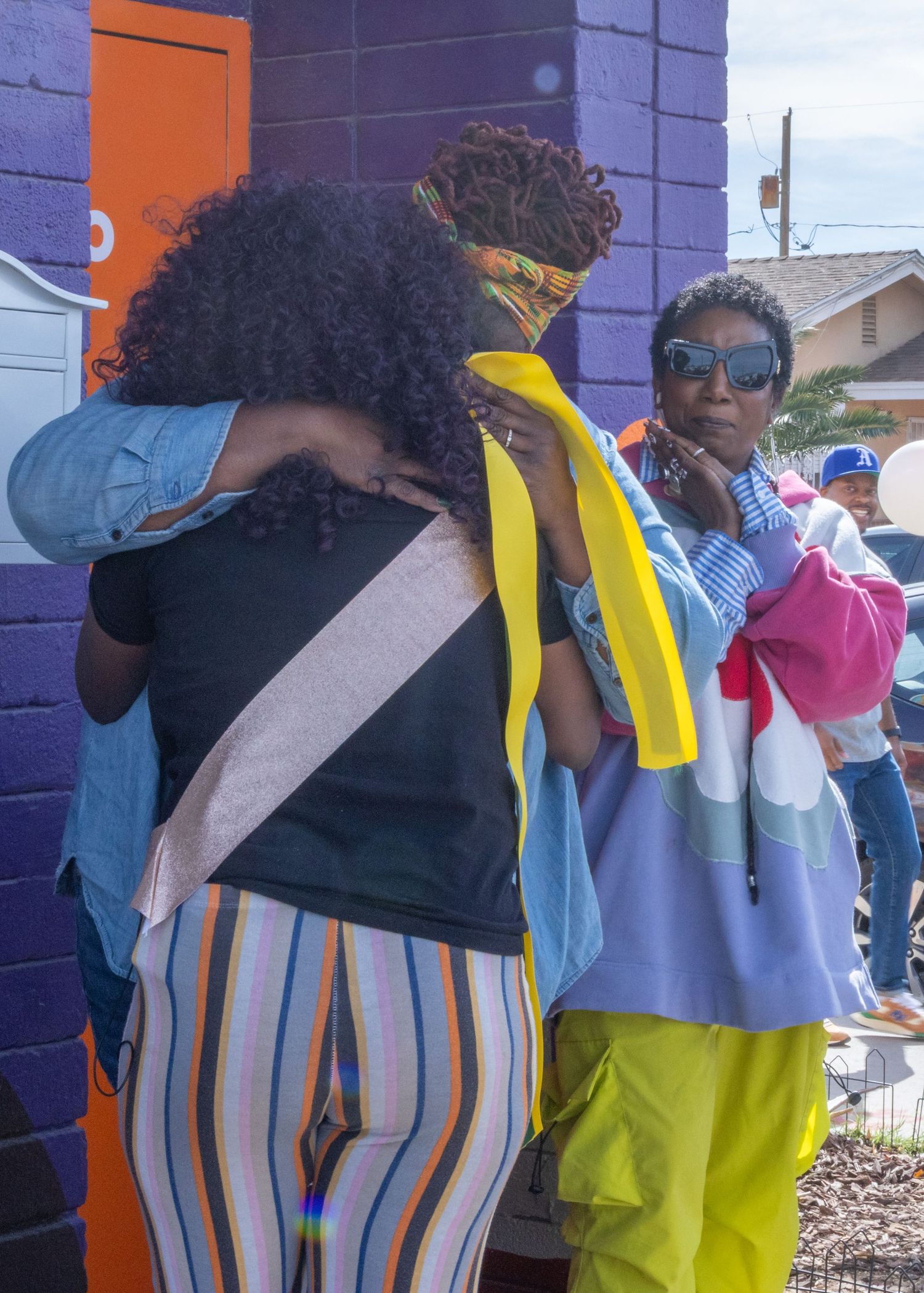 A person wearing a striped jumpsuit and yellow backpack is shown in multiple poses against a purple wall.
