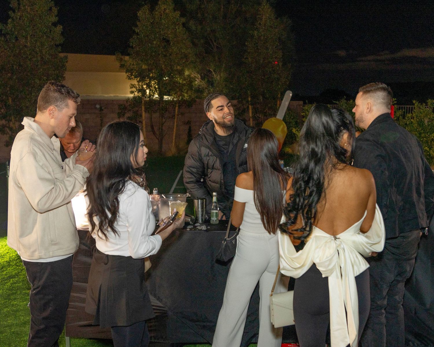 Group of people mingling and socializing at an outdoor nighttime gathering.