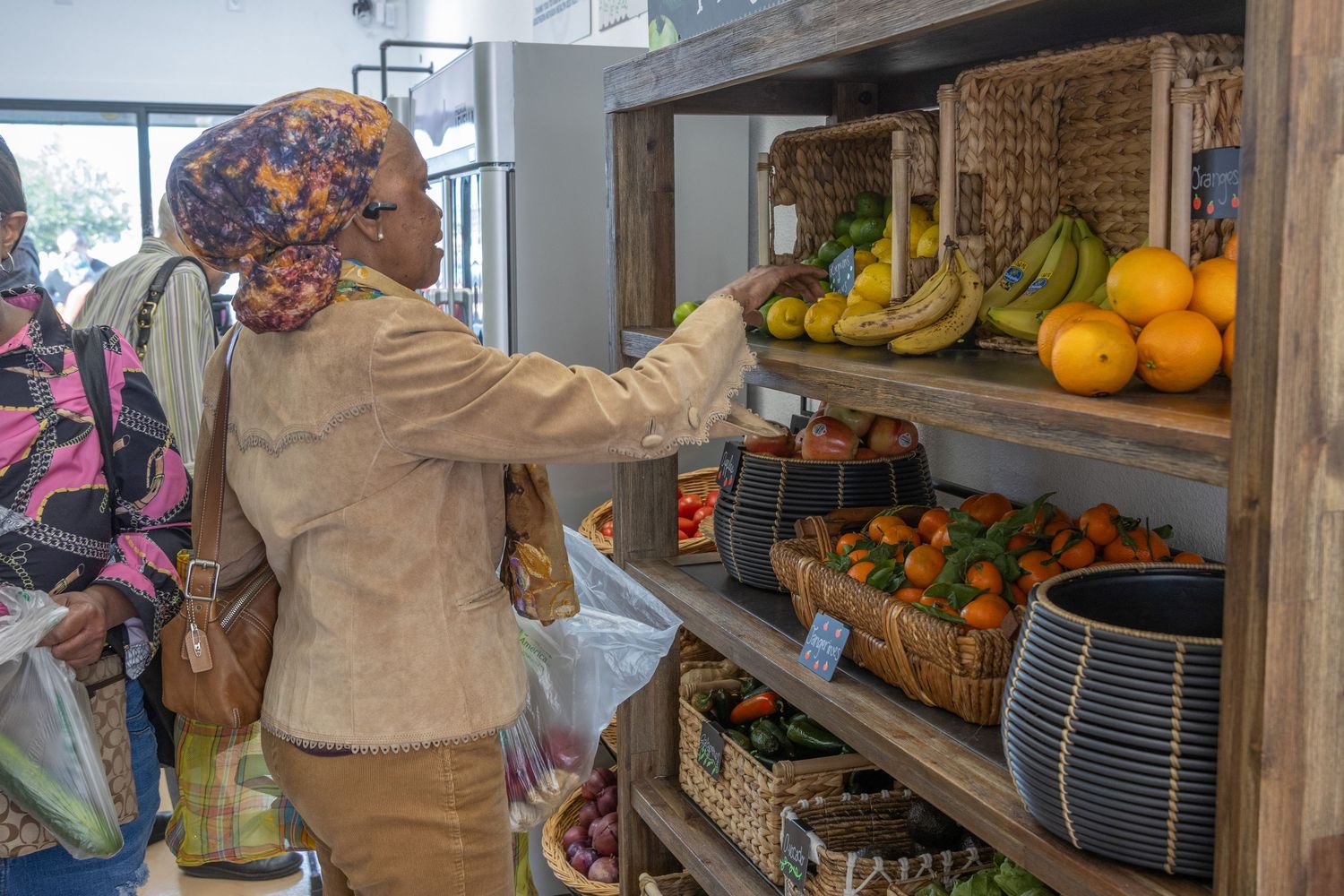 Produce section of a market store displaying fresh fruit, baked goods, and grocery items stocked on wooden shelves.
