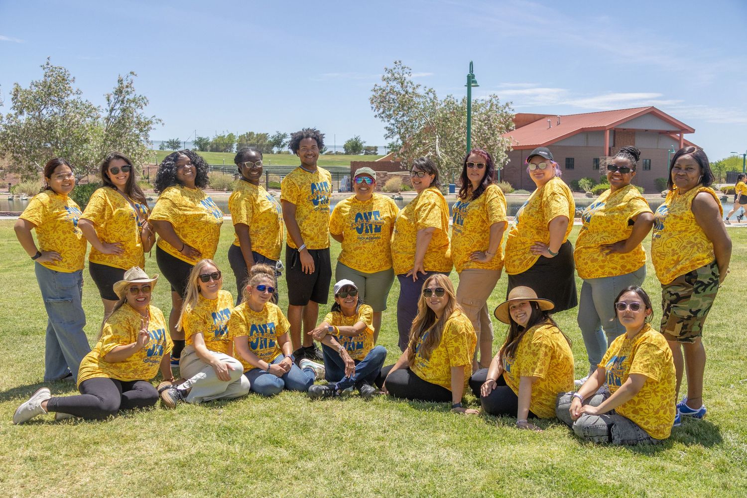 Team members in bright yellow shirts posed together on grass for group picture.