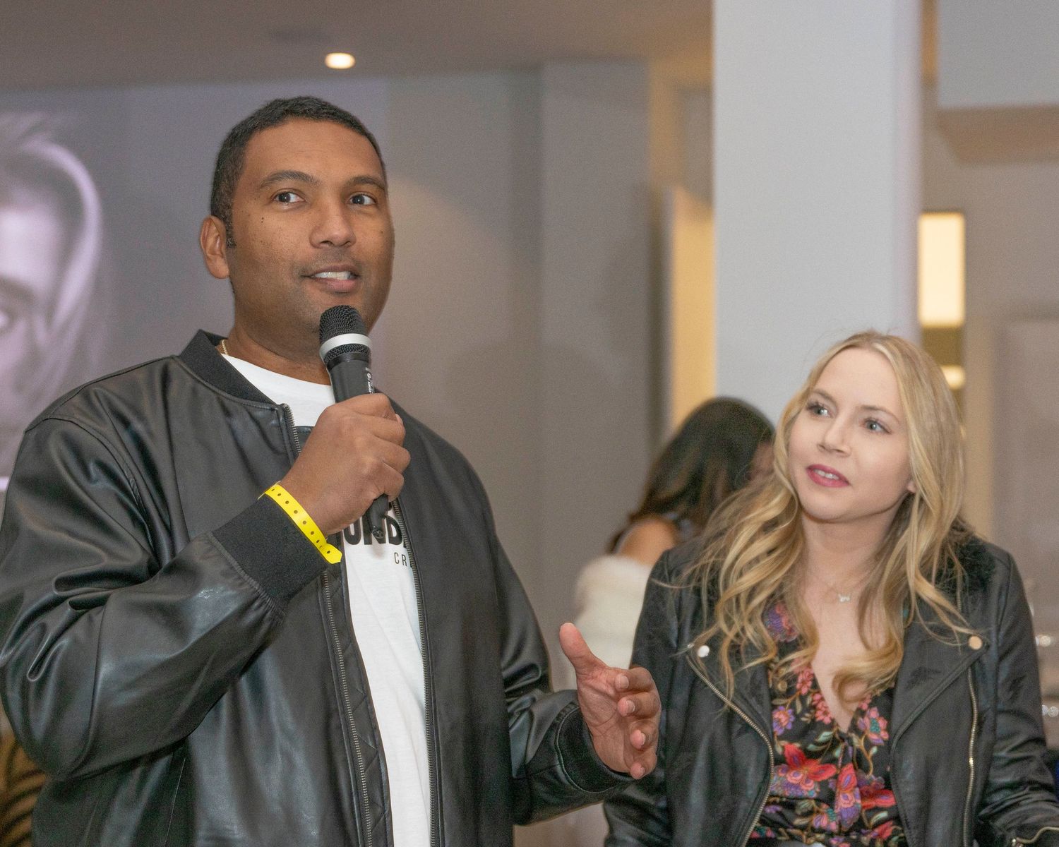 Speakers presenting at an indoor event with professional lighting and audio equipment.