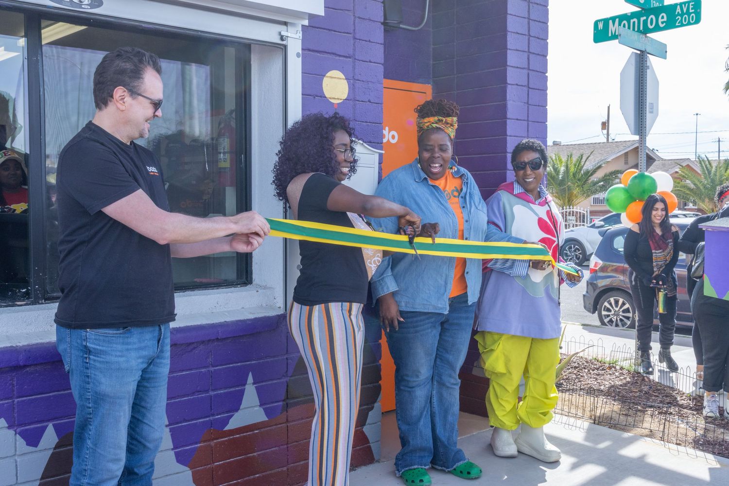 People gather outside a purple building for a measuring activity near a street sign.