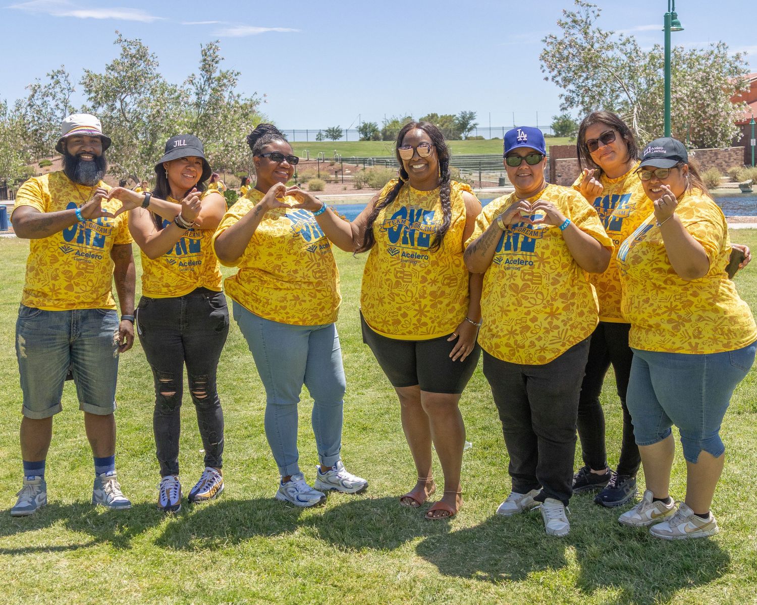 Row of people wearing matching yellow shirts standing together on grassy field.